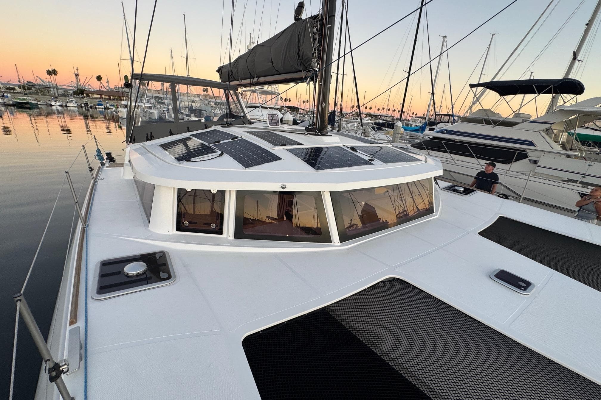 Modern NEEL 43 trimaran docked at sunset, featuring solar panels on deck.