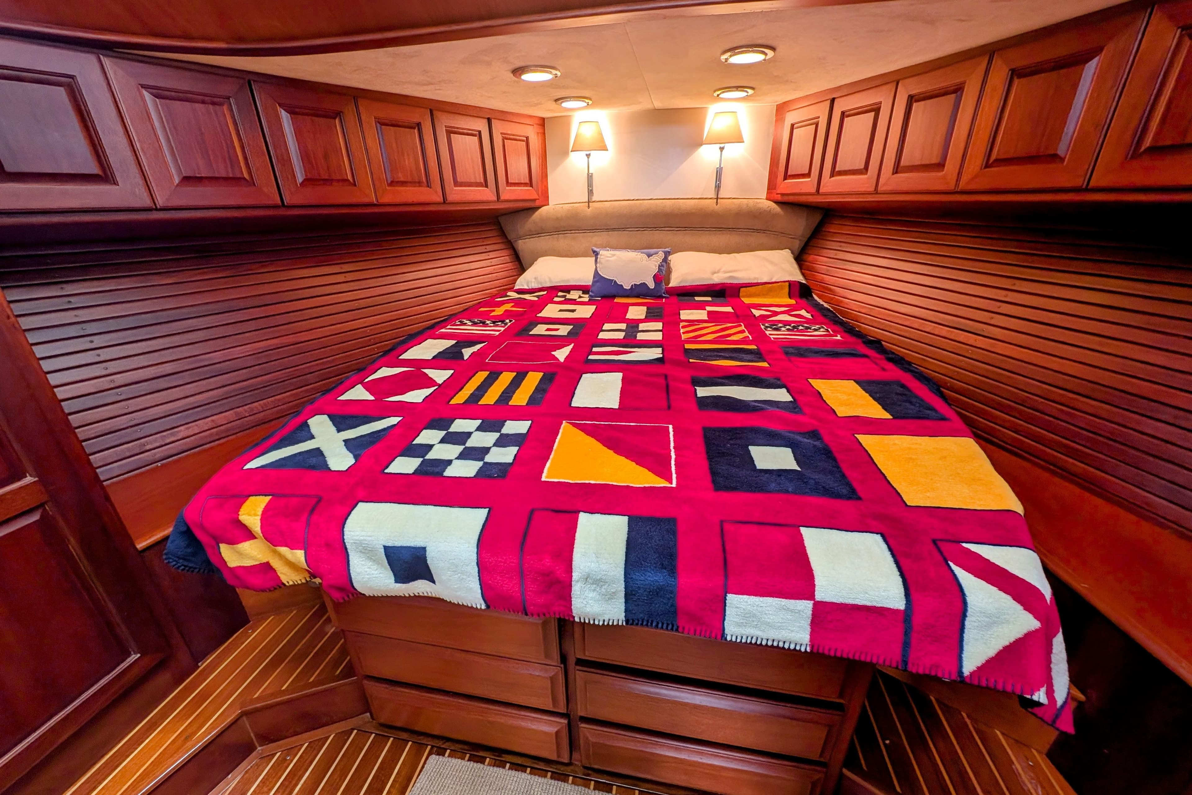 Luxurious 2002 Legacy Yachts 52 Express cabin with nautical-themed bedding and elegant wood paneling.