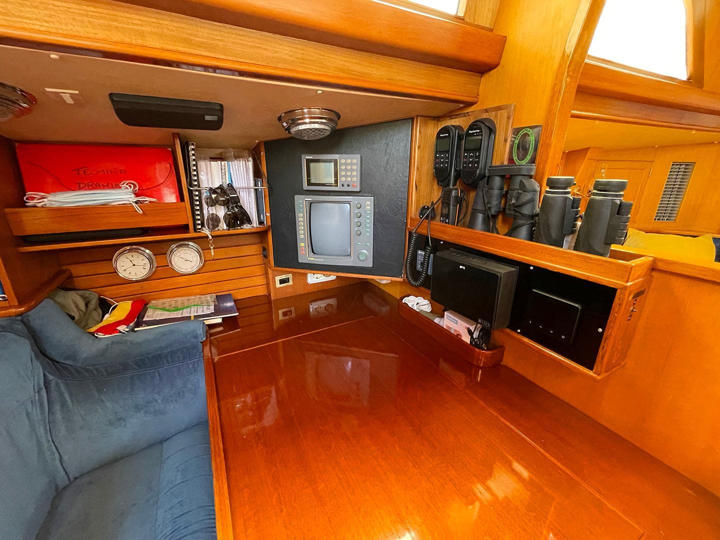Navigation station inside 1985 Camper & Nicholsons 58 yacht with instruments and seating.