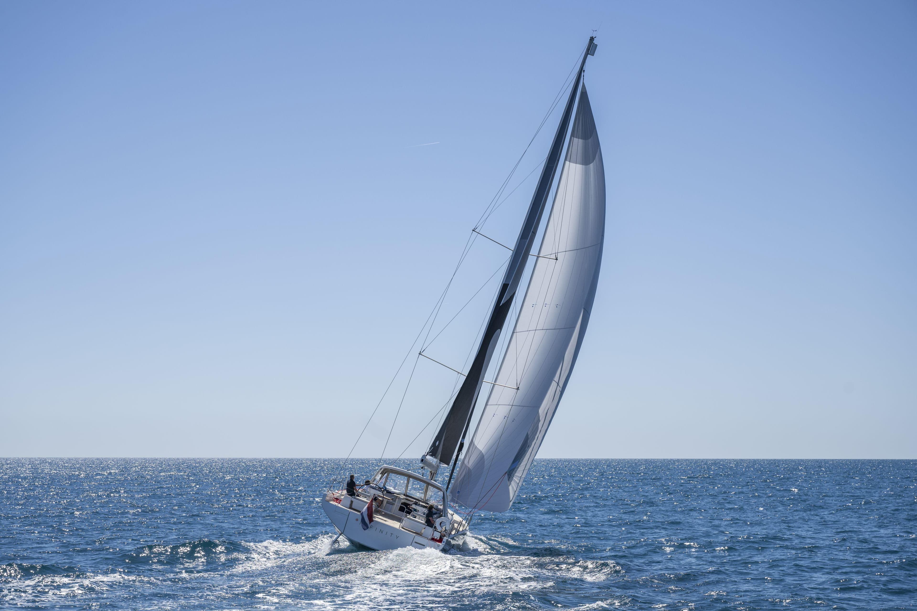 2023 Beneteau Oceanis Yacht 60 sailing on open sea under clear blue sky.