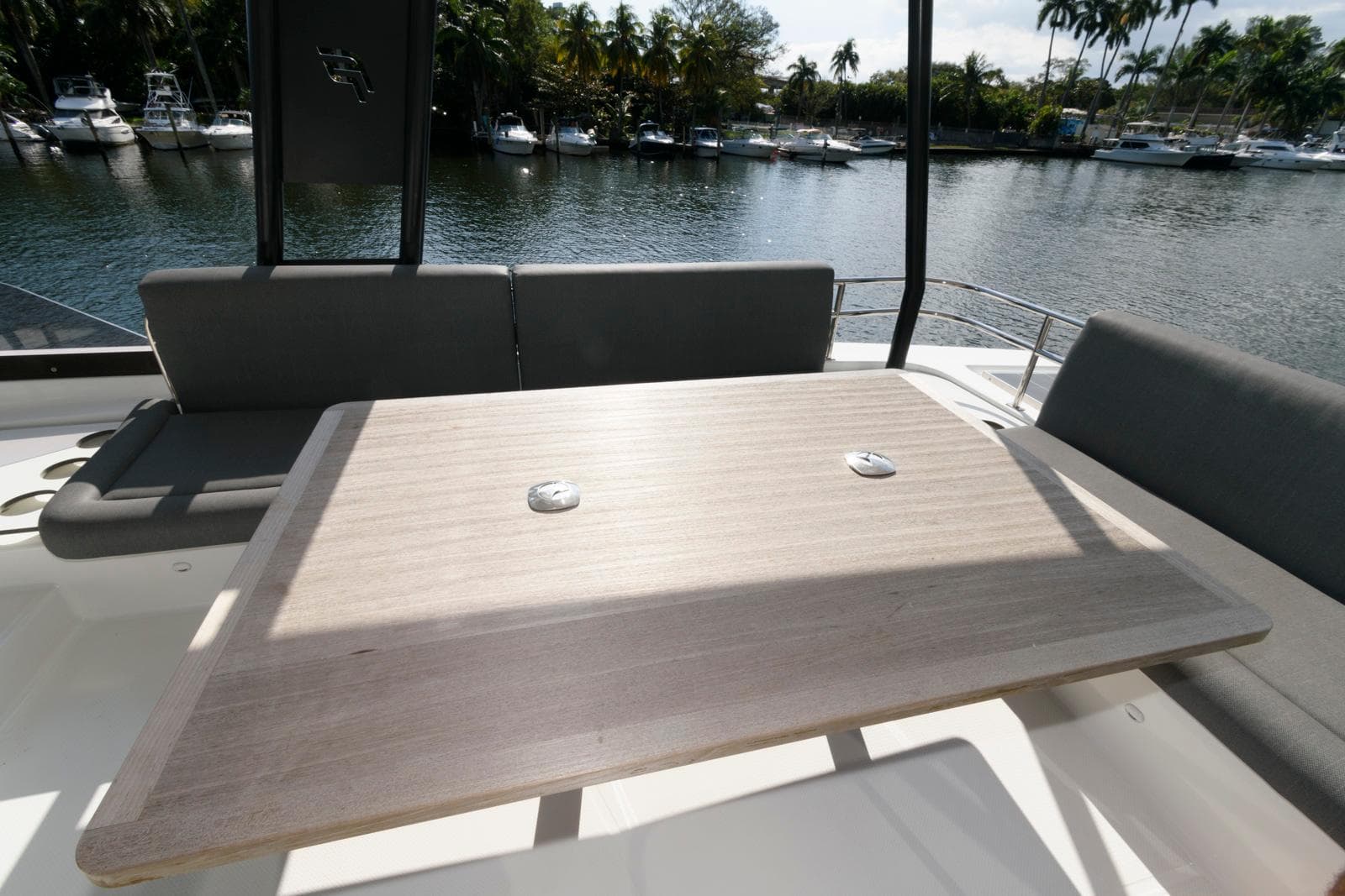 2022 Fountaine Pajot MY6 yacht deck with seating and table, overlooking a serene waterfront.