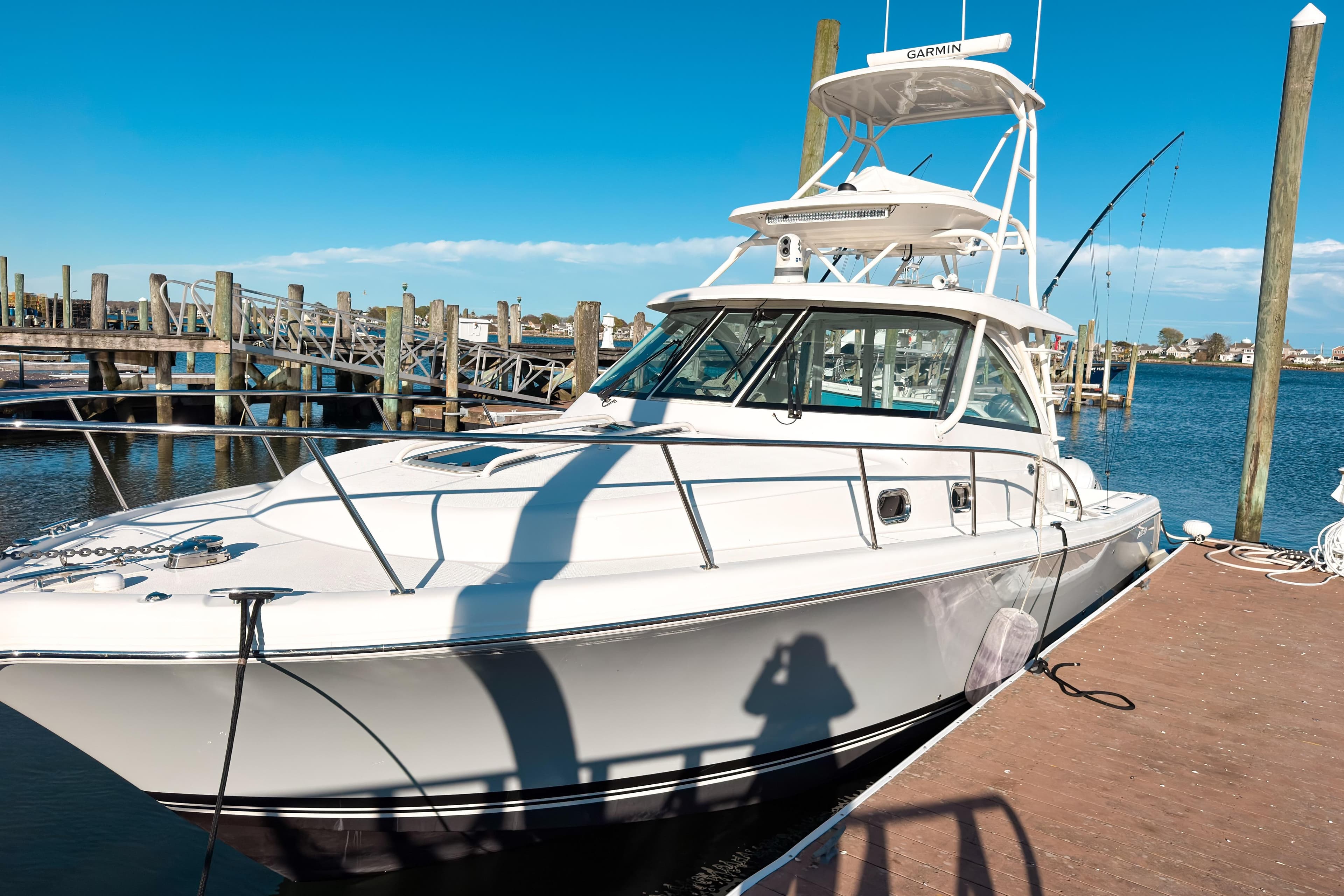 2021 Pursuit OS 385 Offshore boat docked at marina under clear blue sky.