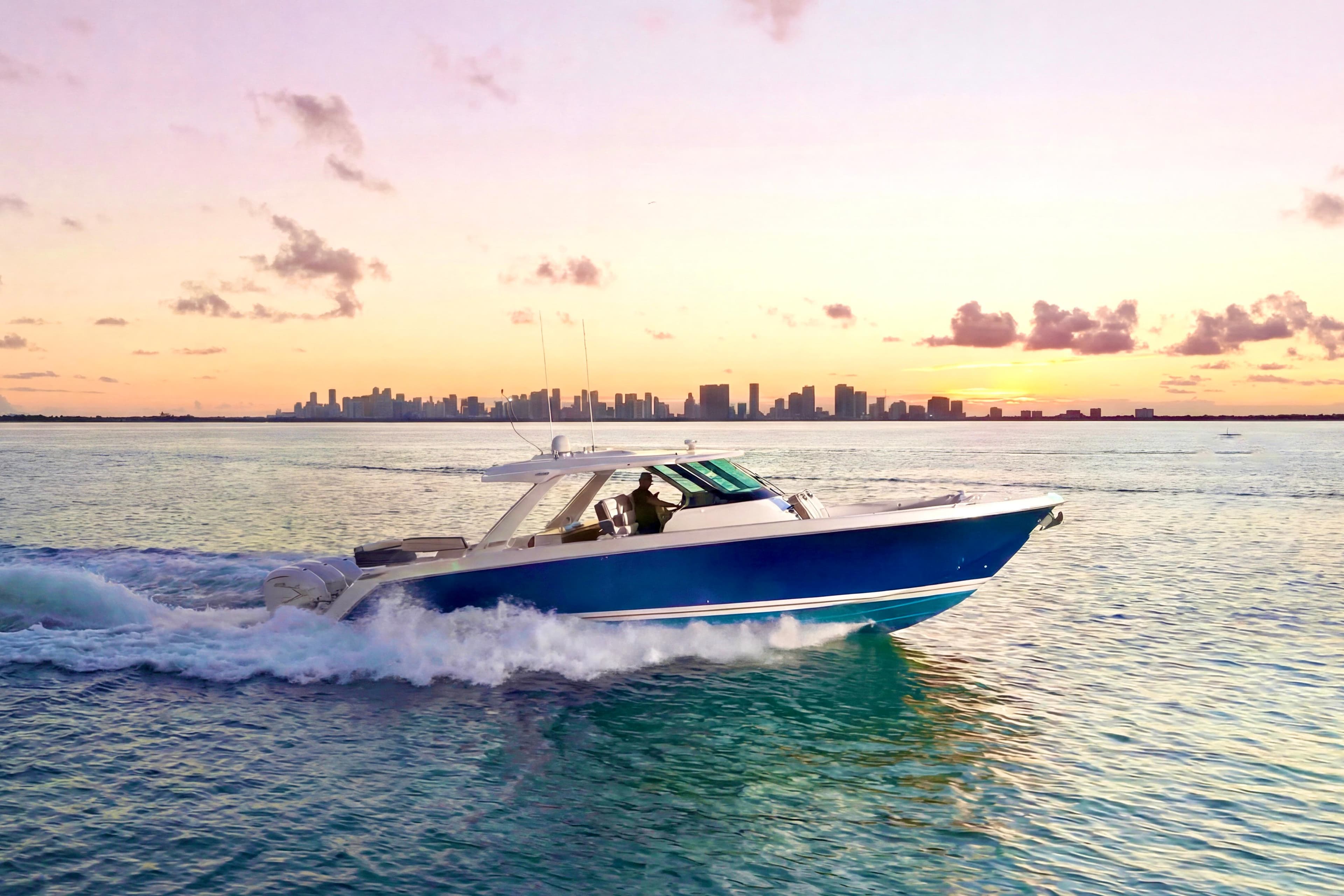 2020 Tiara Yachts 43 LS cruising at sunset with city skyline in background.
