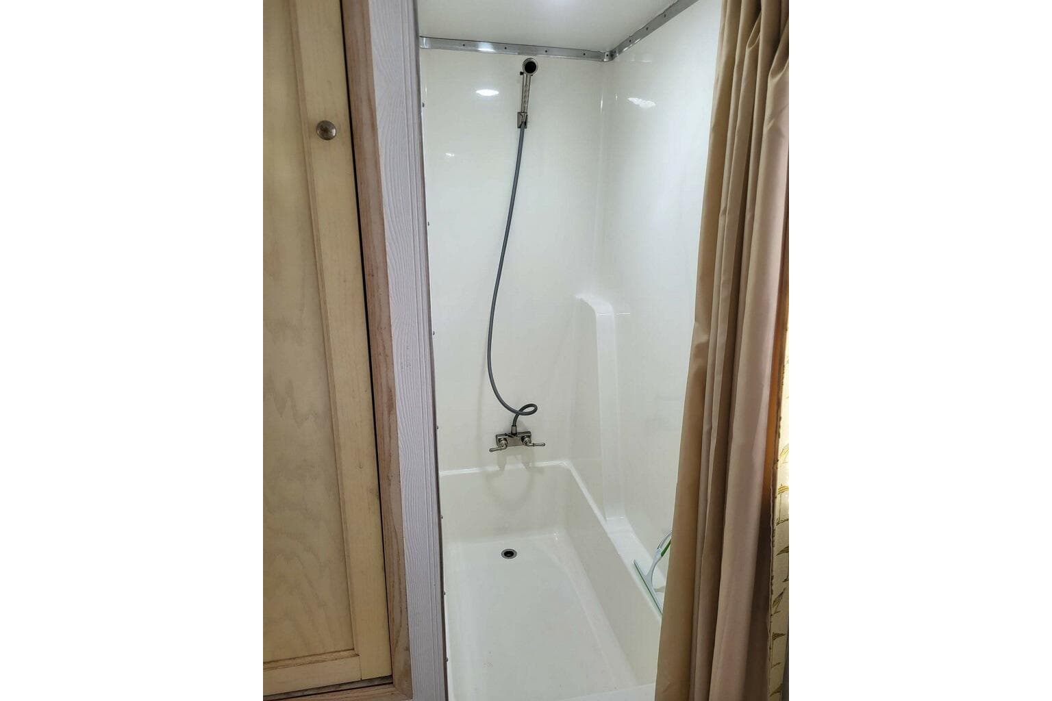 Shower area in 1996 Gibson 50 Cabin Yacht with curtain and handheld showerhead.