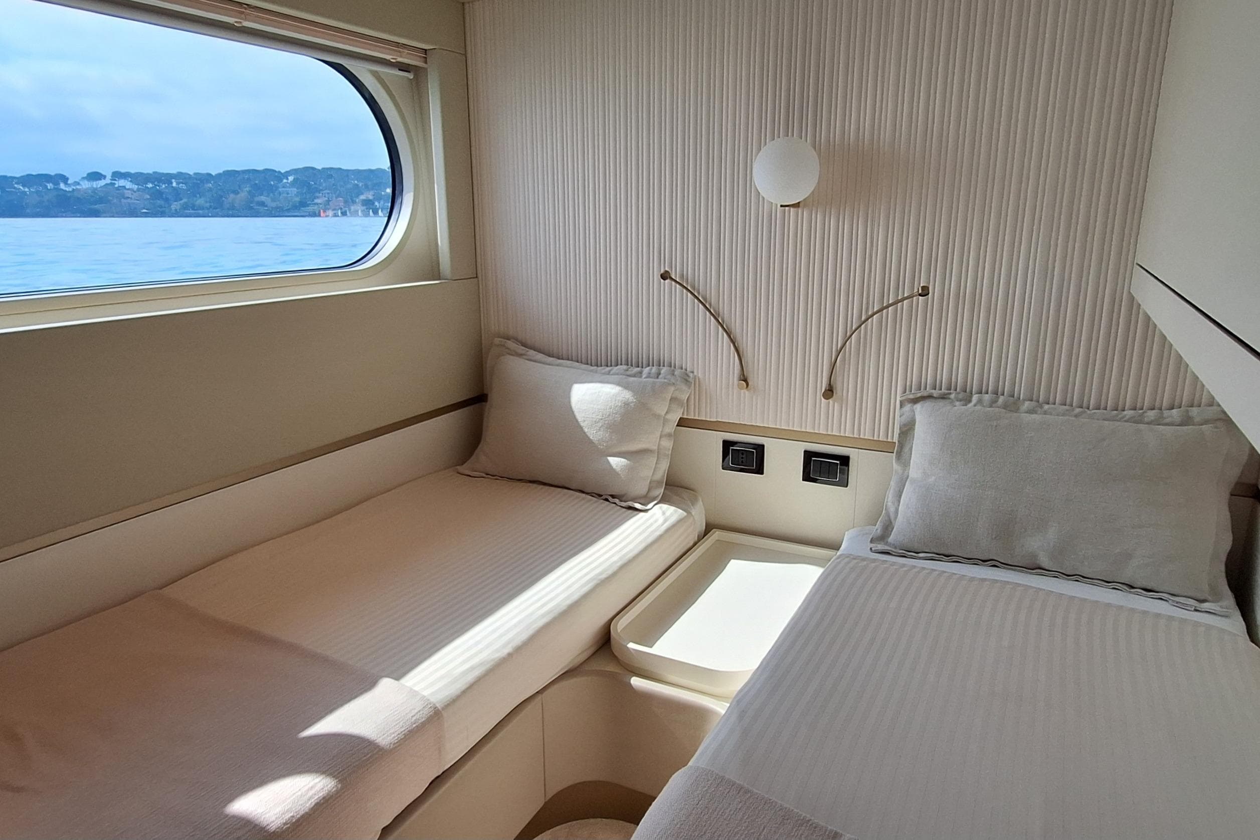 Luxurious cabin interior of 2022 Azimut Magellano 25M yacht with twin beds and ocean view.