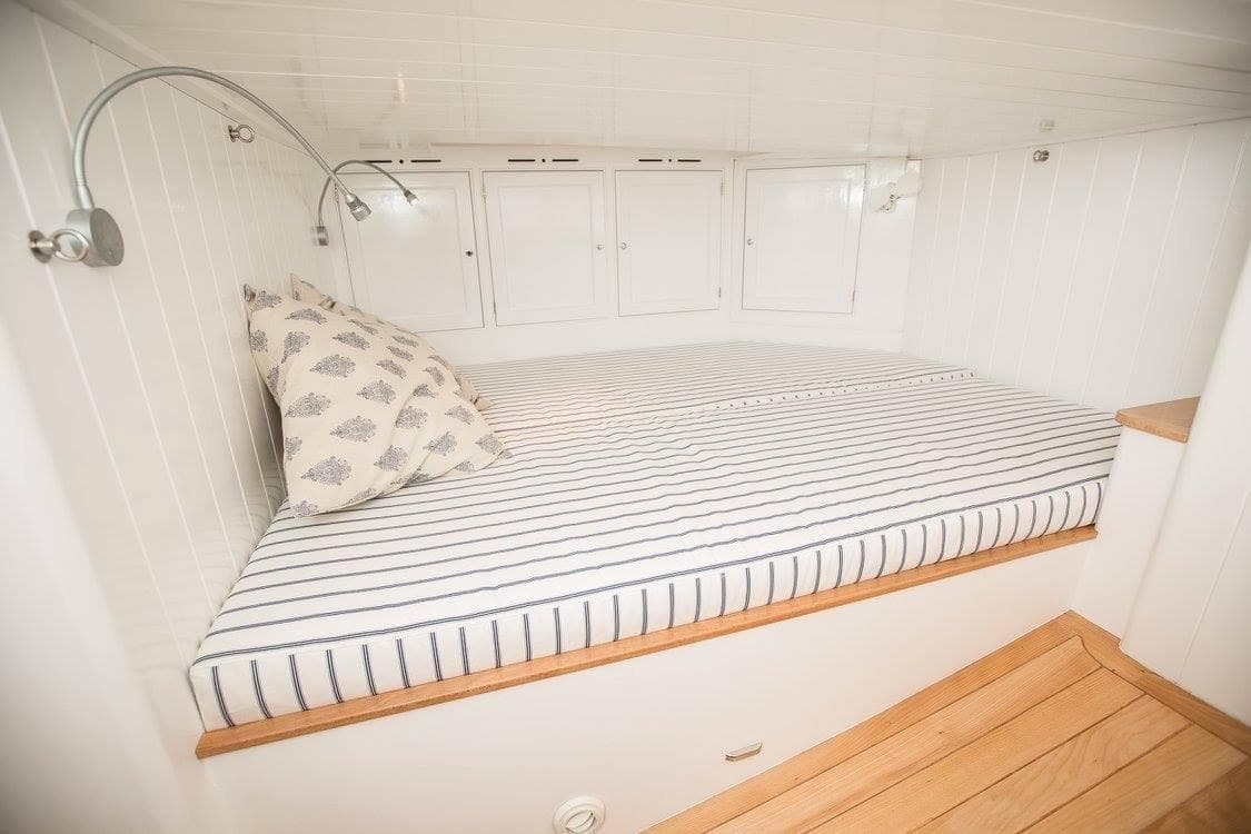 Cozy cabin interior of 2016 Ed Joy Good Hope 56 with striped bedding and reading lights.