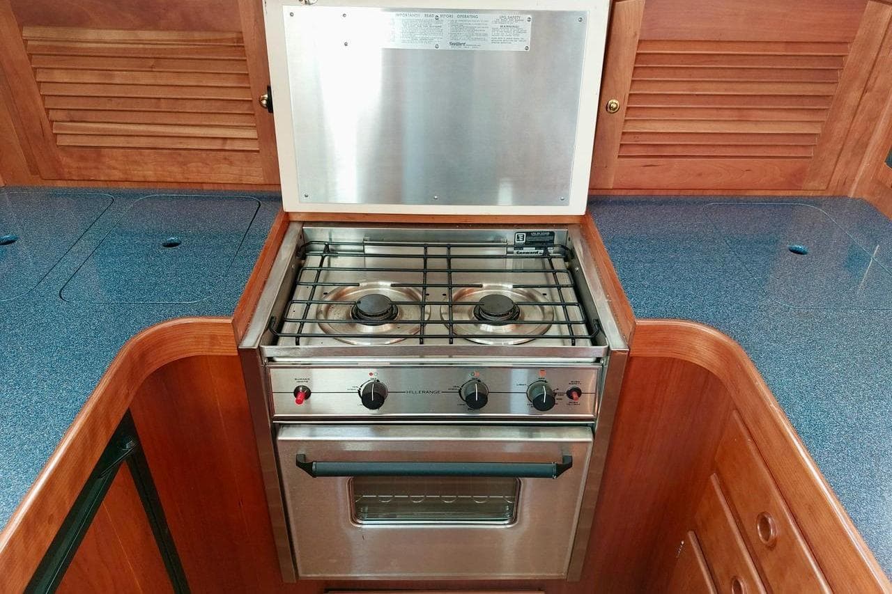 2001 Sabre 36 Express yacht kitchen with stainless steel stove and wooden cabinetry.