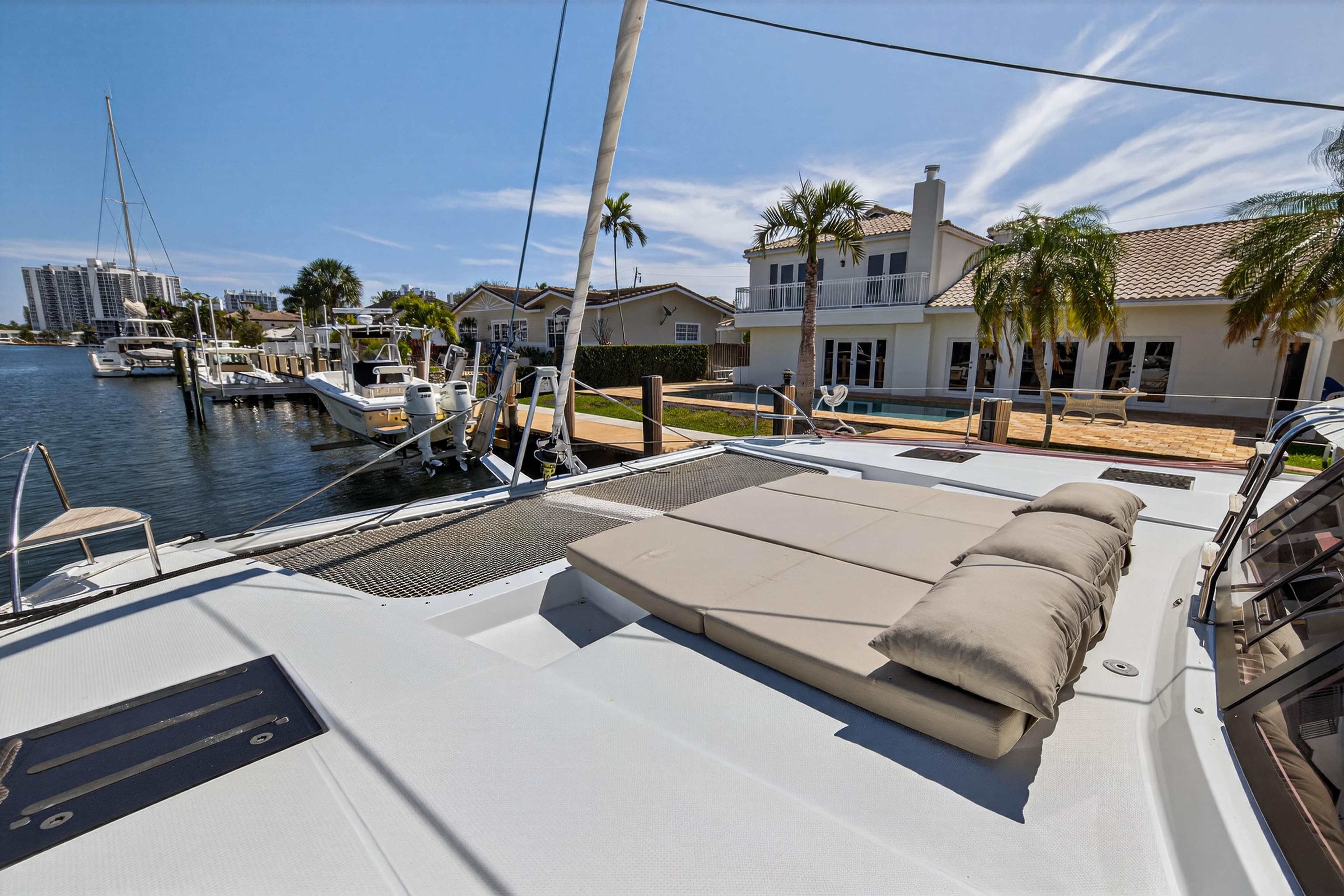 2022 Fountaine Pajot Tanna 47 catamaran docked near waterfront homes, featuring spacious deck.