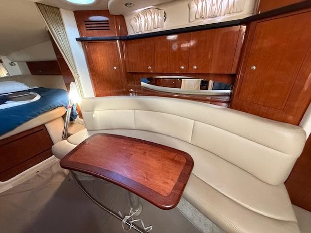 2007 Sea Ray 320 Sundancer interior with curved seating and wooden table.