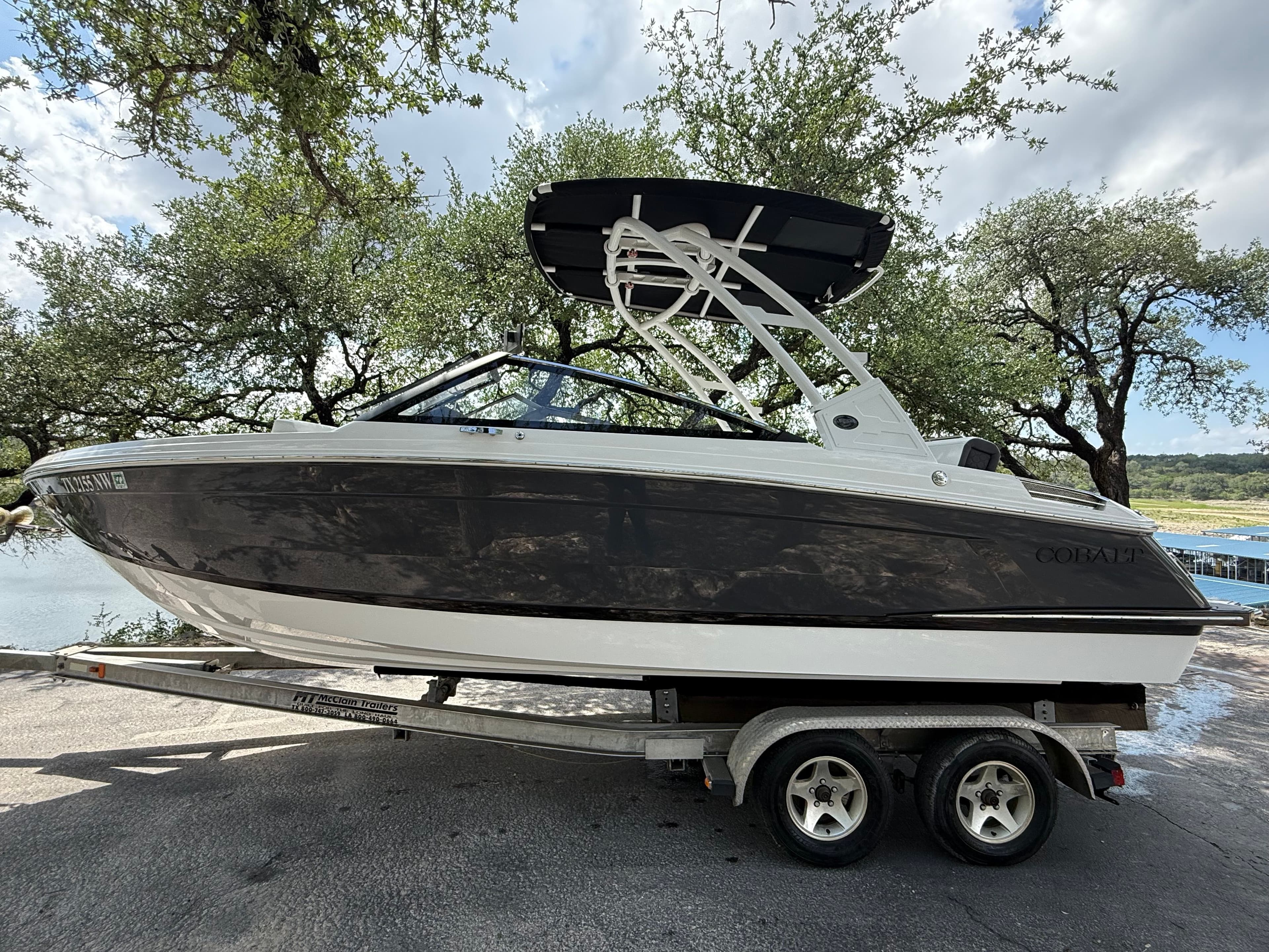 2025 Cobalt R4 boat on trailer, surrounded by trees.