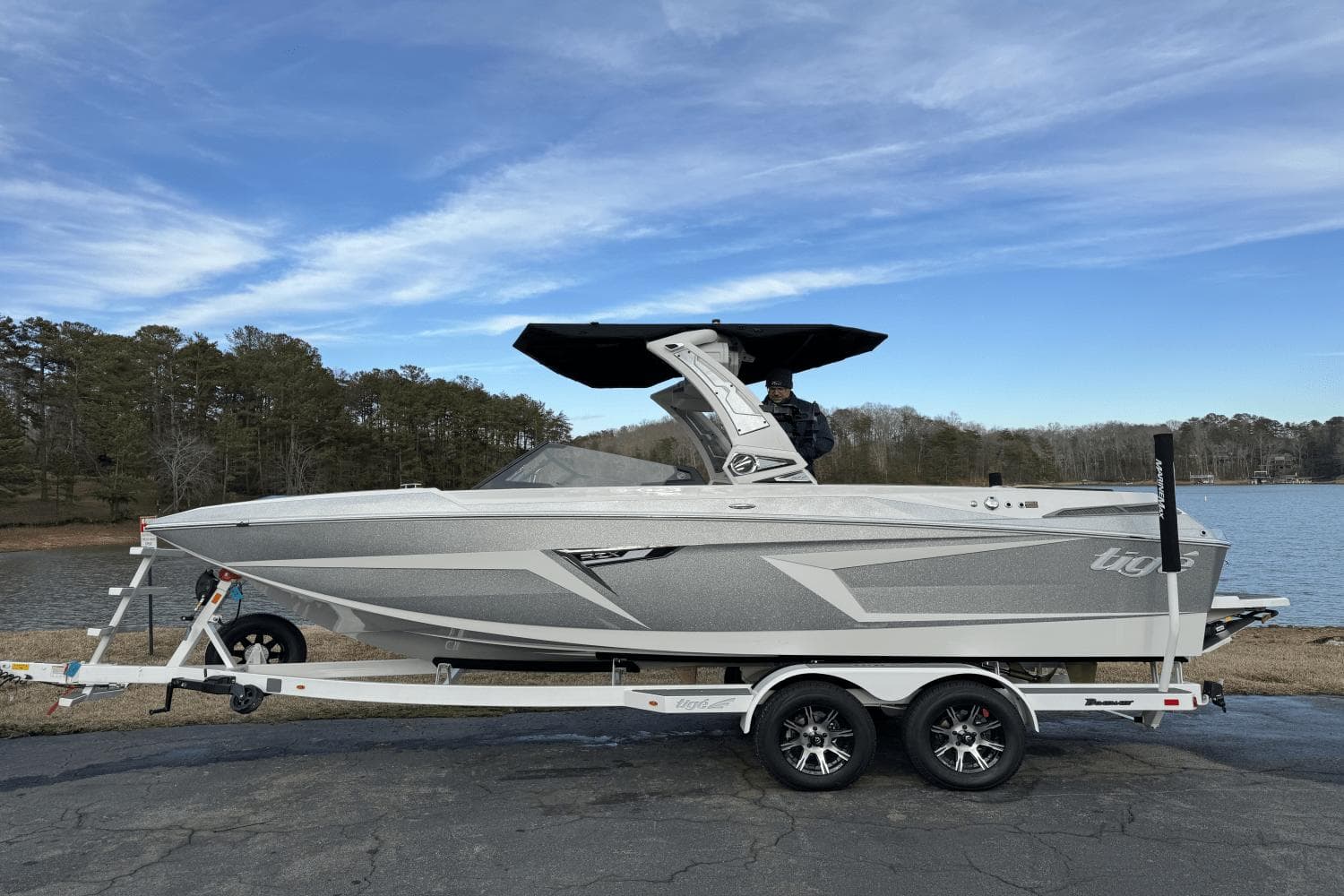 2024 Tigé RZX22 boat on trailer by a lake with trees in the background.