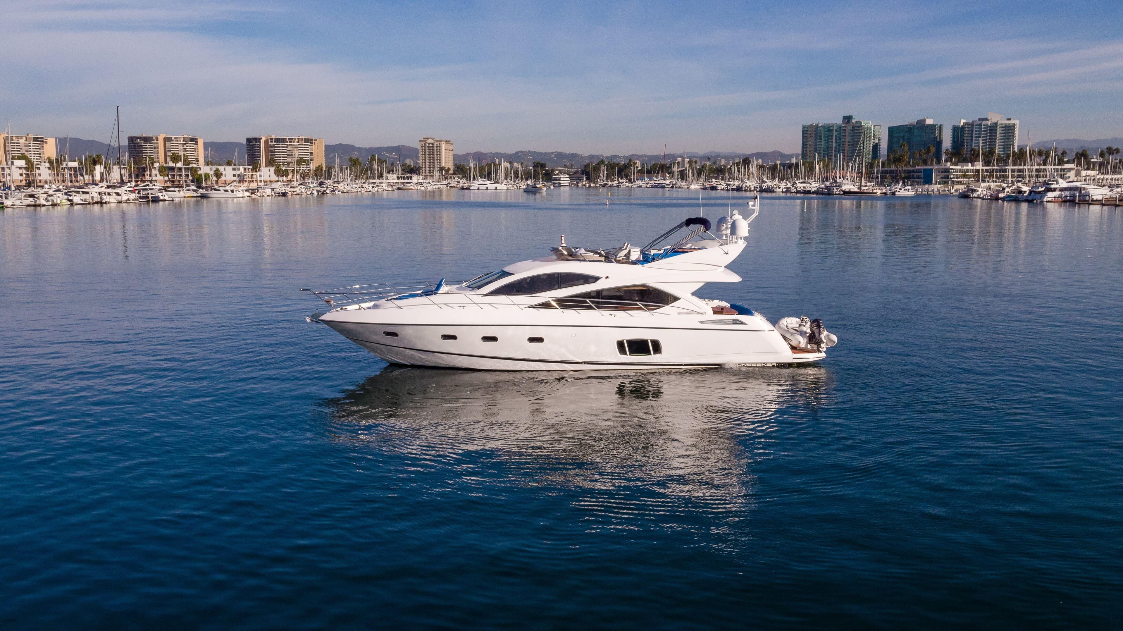 2010 Sunseeker Manhattan 60 yacht on calm water with cityscape background.