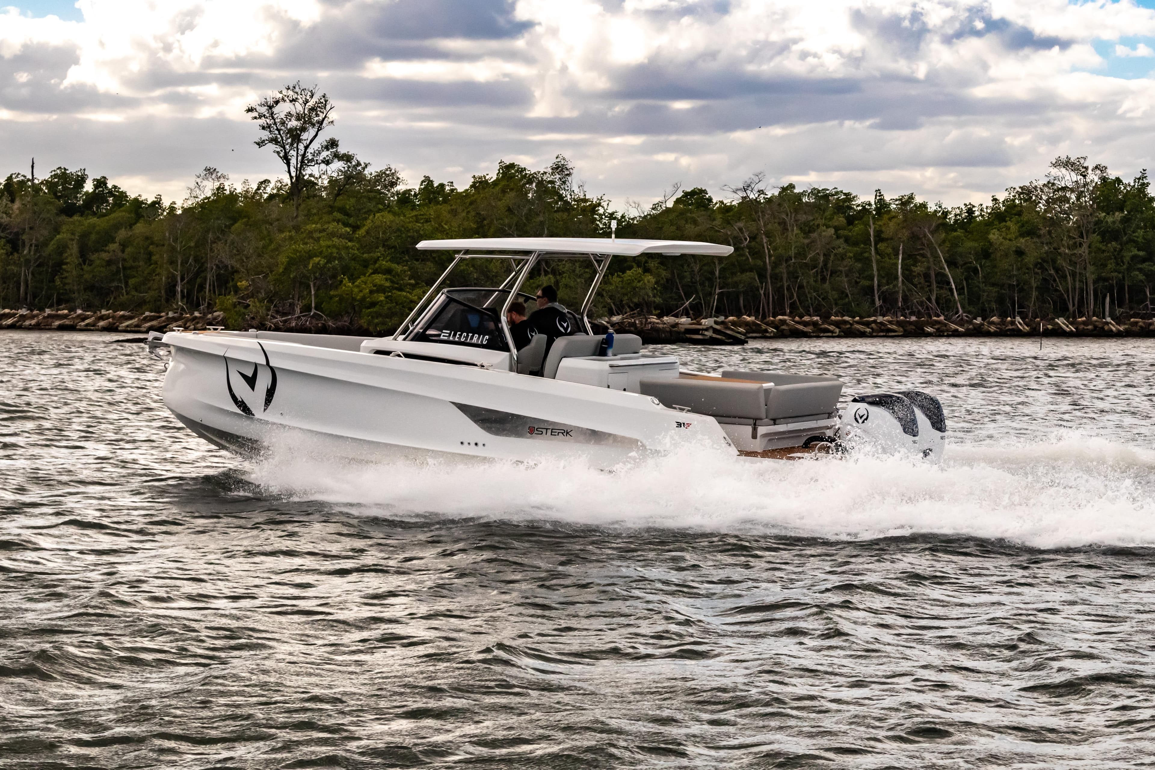 Electric STERK 31 boat cruising on water, 2025 model, with lush greenery in background.