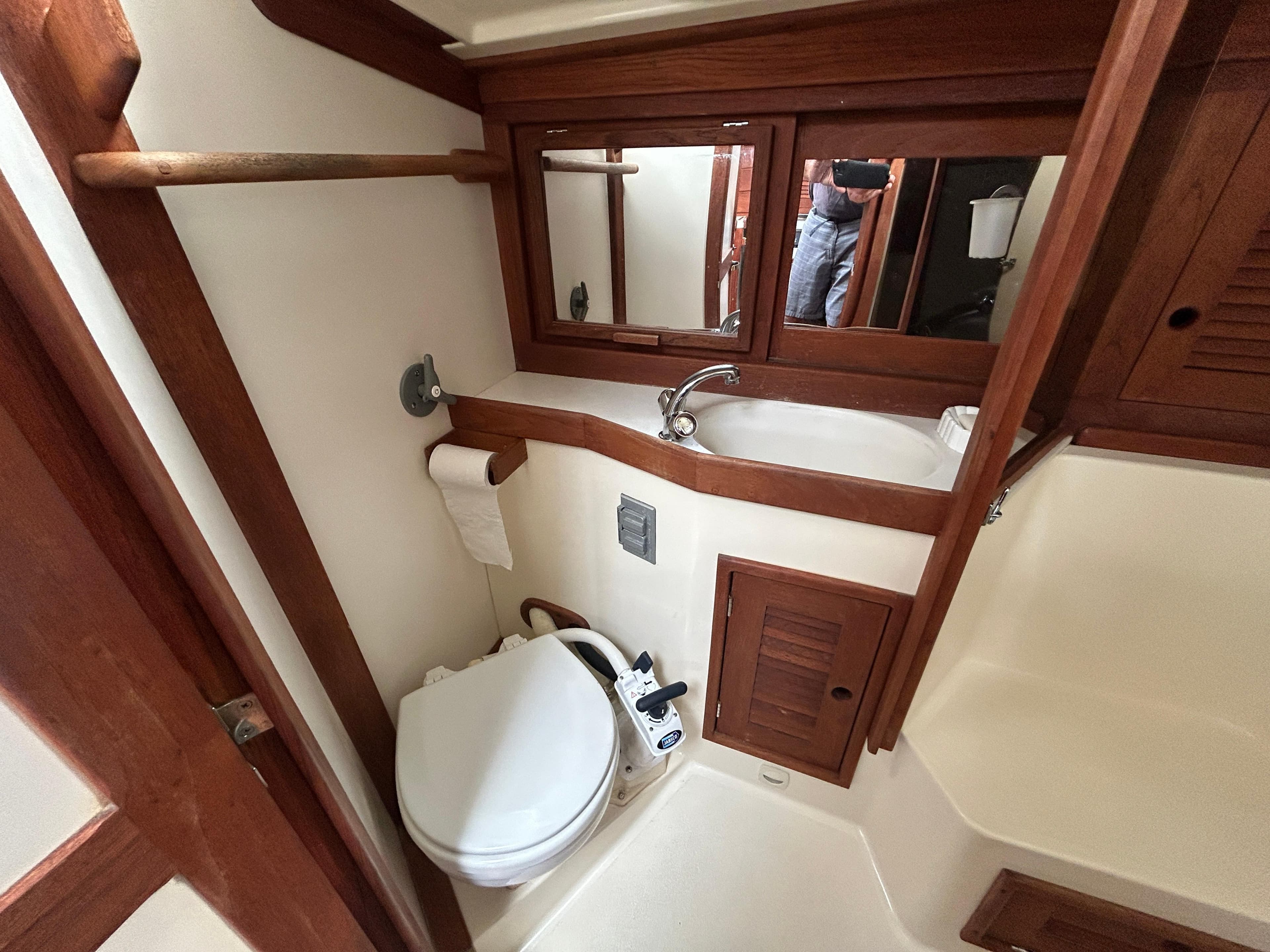 Compact bathroom in 1998 Tartan 3500 yacht with wooden accents and mirror.