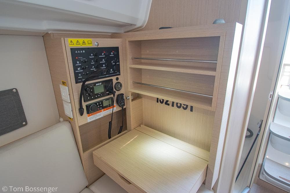 Navigation station in 2022 Beneteau Oceanis 30.1 yacht with control panel and storage shelves.
