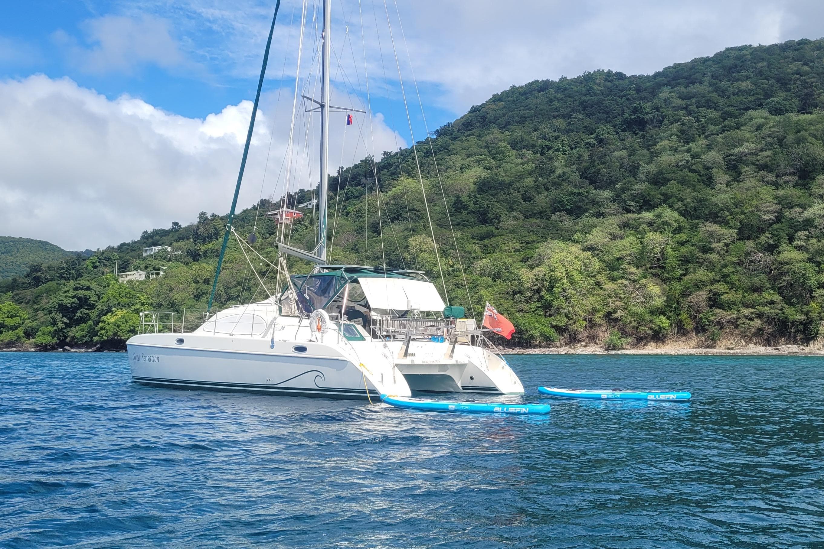 Sailing catamaran Prout 38 (1998) anchored near lush green island coast.