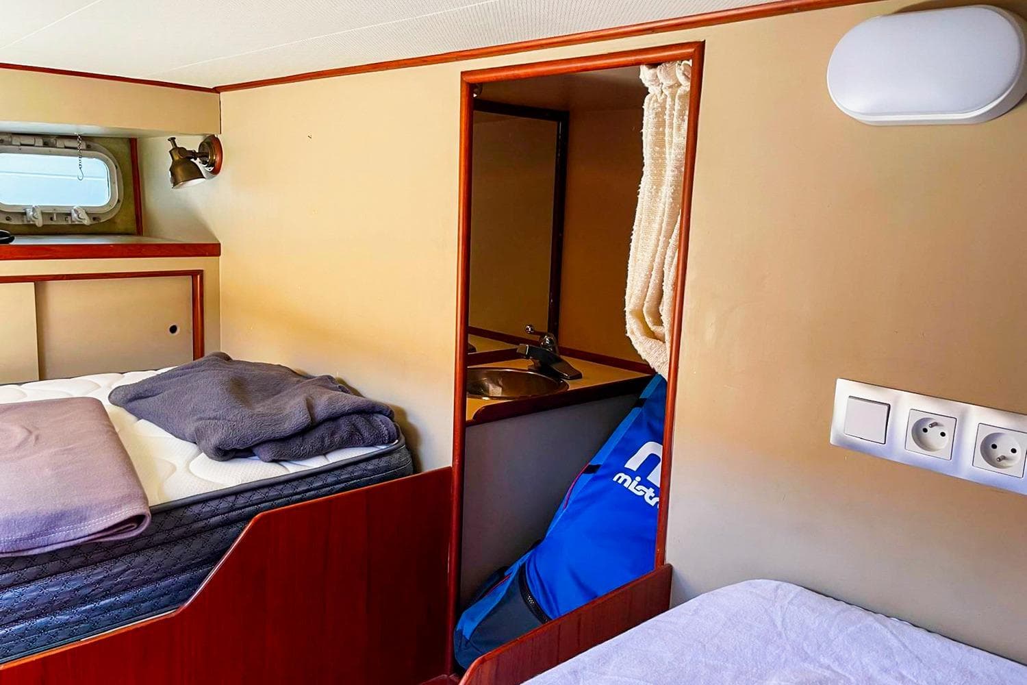 Cozy cabin interior of 1980 Grand Banks 42 Europa yacht with bed and porthole.