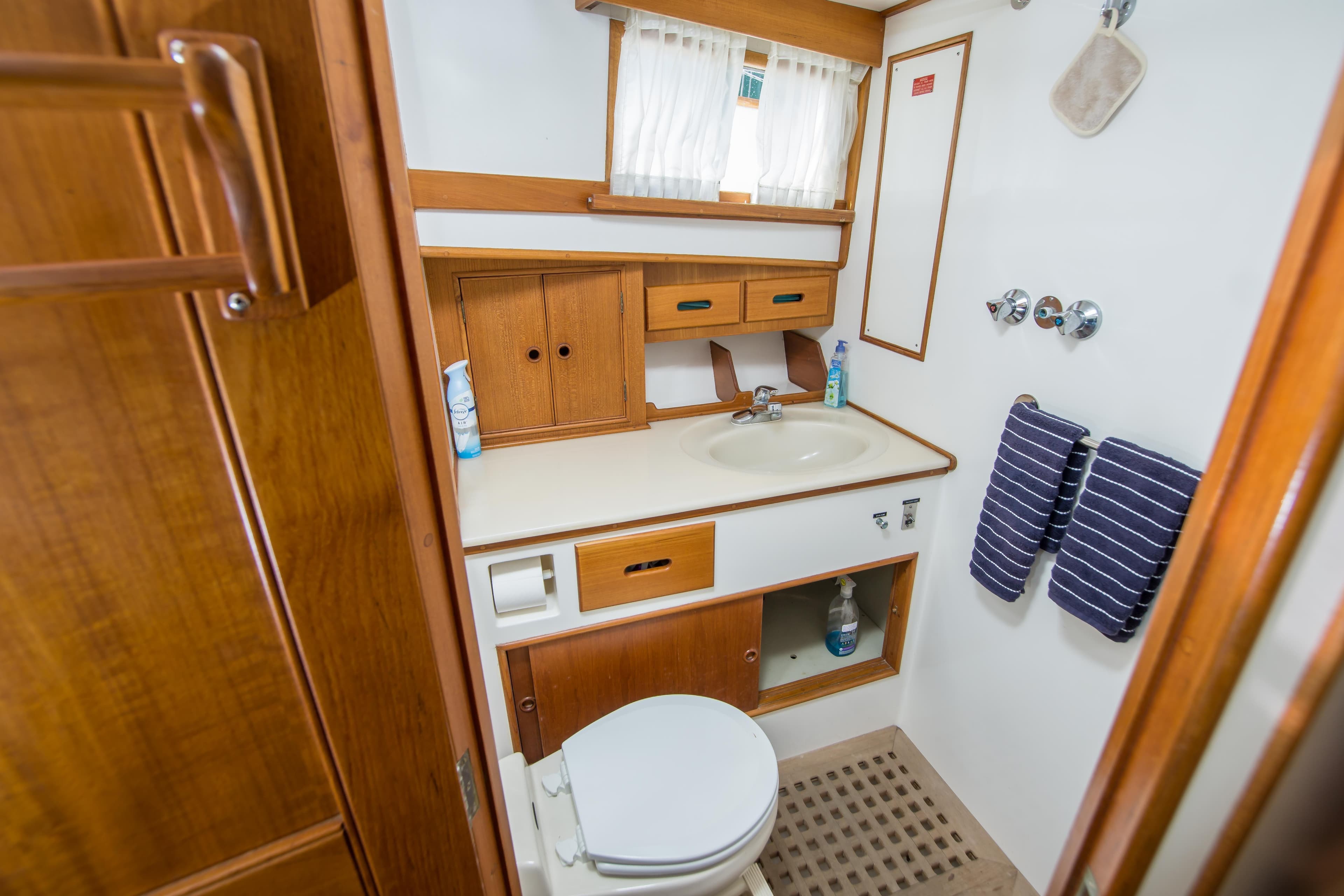 Bathroom interior of 1995 Grand Banks 42 Classic yacht, featuring wood cabinetry and nautical decor.