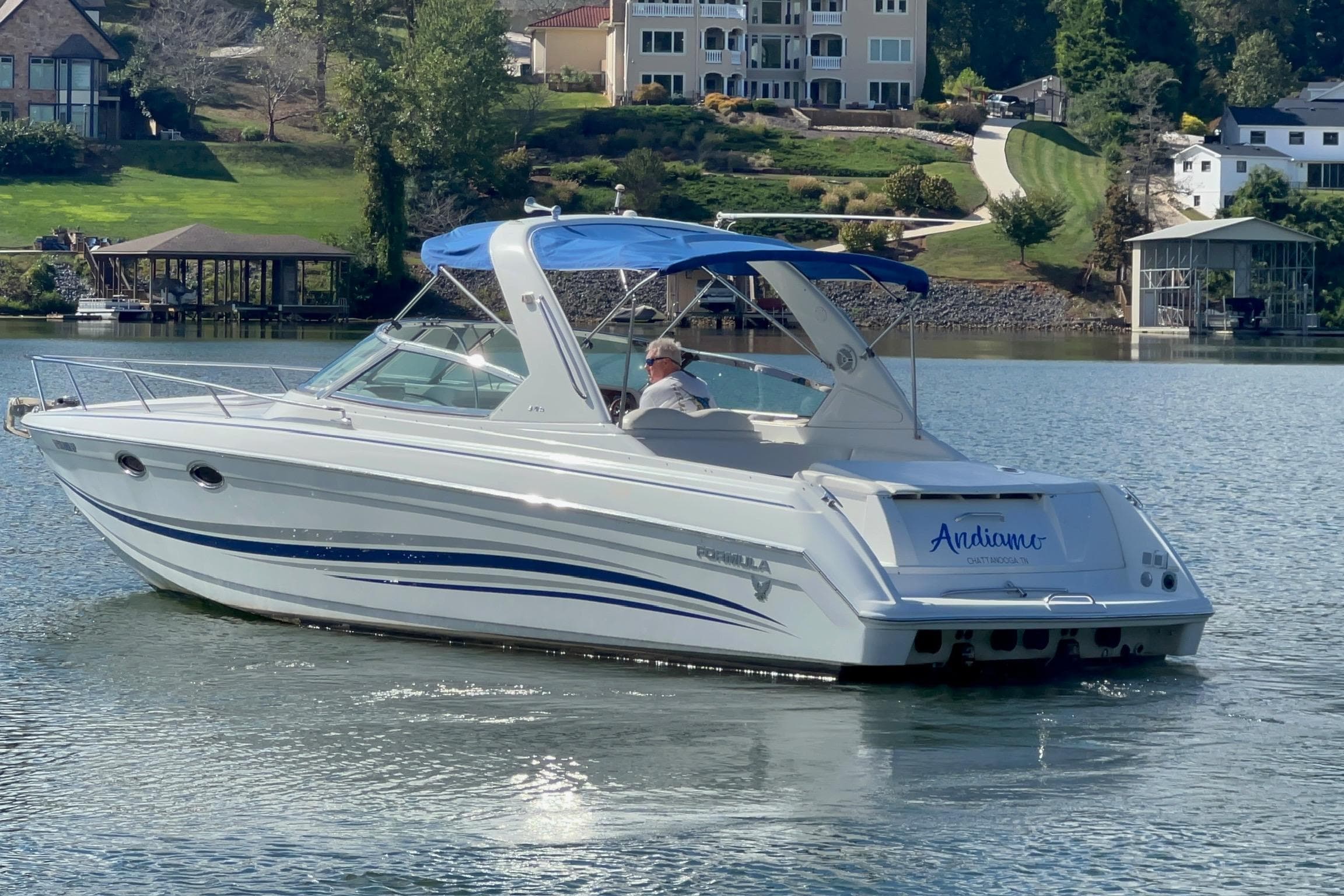 2004 Formula 330 Sun Sport boat cruising on a scenic lake with waterfront homes.