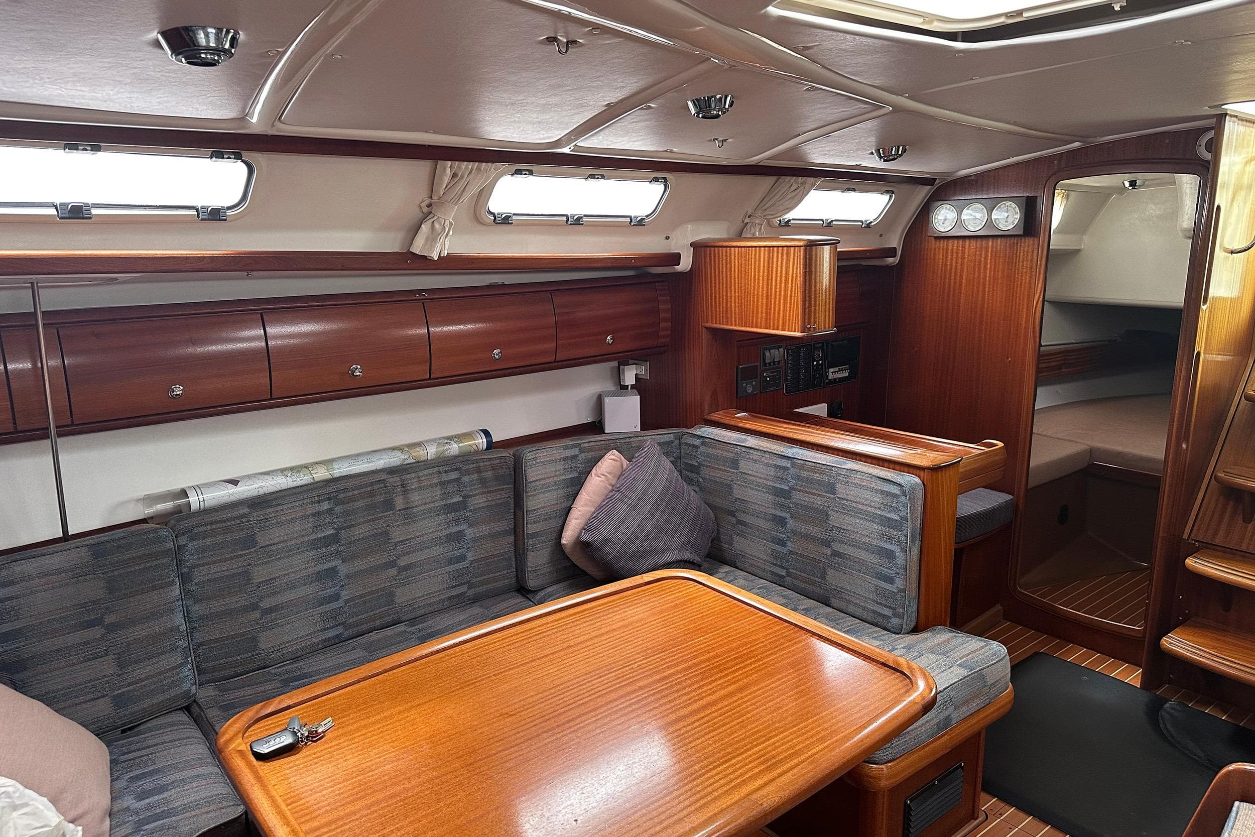 Interior of a 2003 Bavaria 44 yacht with wooden furnishings and cozy seating area.