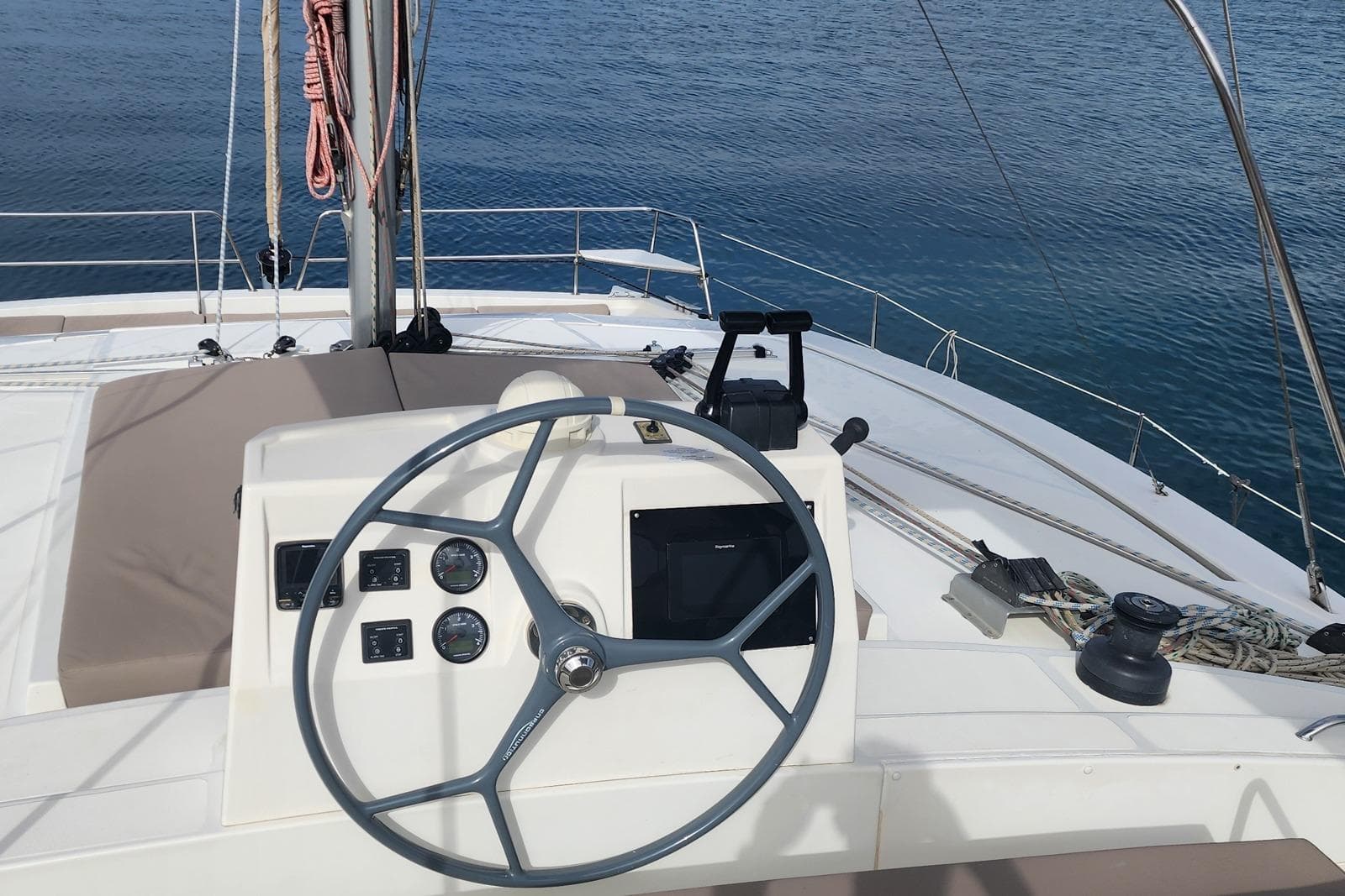 Steering wheel of a 2016 Bali 4.5 catamaran on calm blue waters.