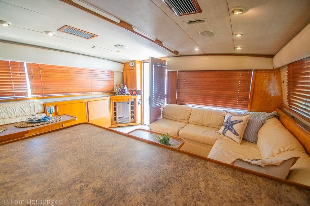 Interior of 1989 Bertram 50 Convertible yacht with cozy seating and wooden blinds.