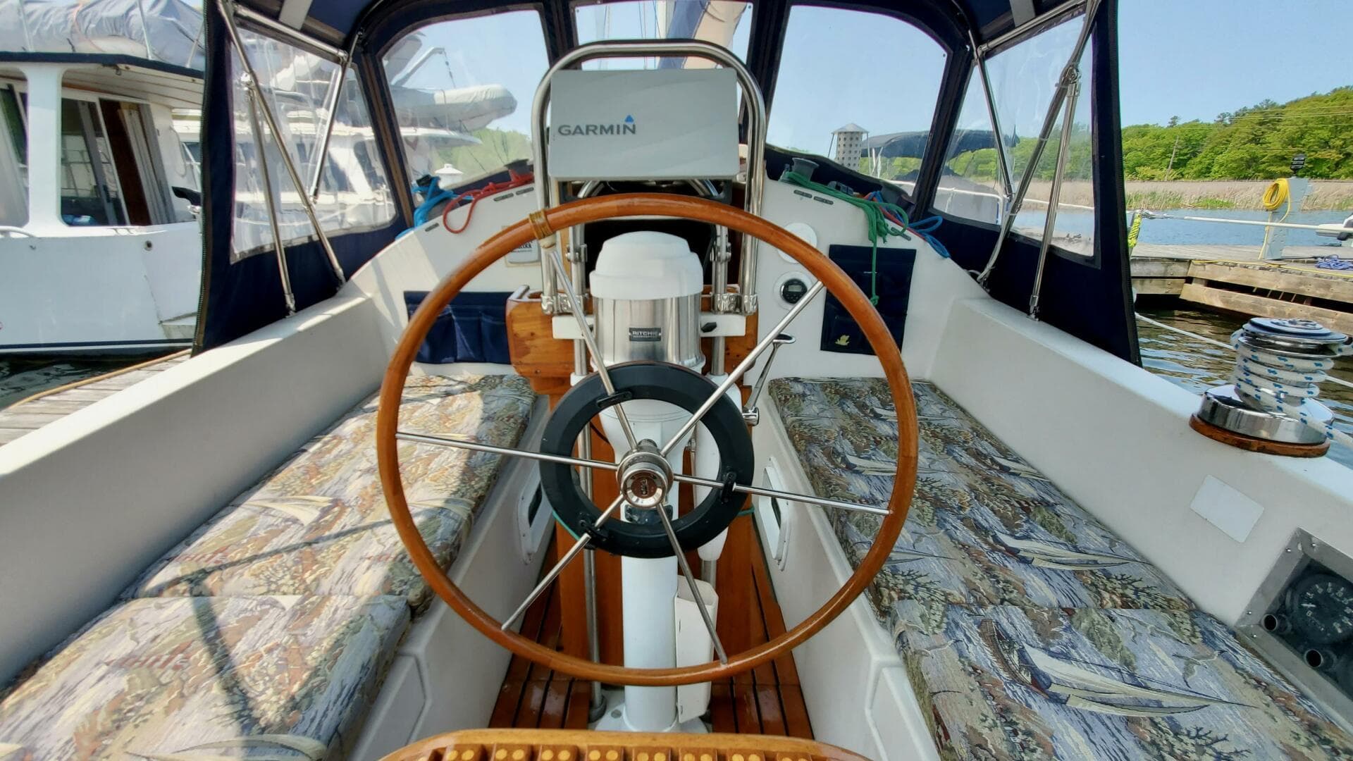 1982 Hinterhoeller Nonsuch sailboat cockpit with wooden wheel and patterned seating.
