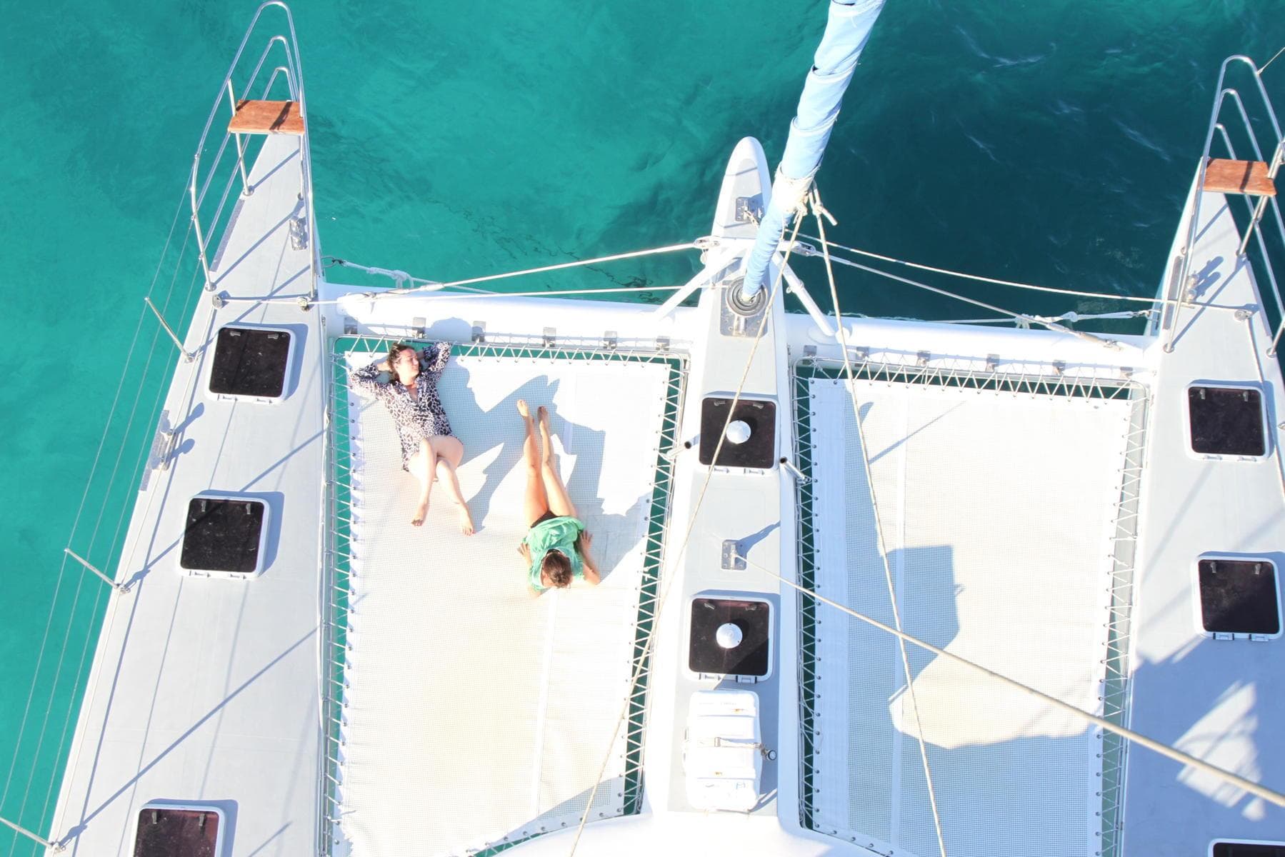 Two people relaxing on a 2007 Custom ISoCatamarans 60 in clear blue water.