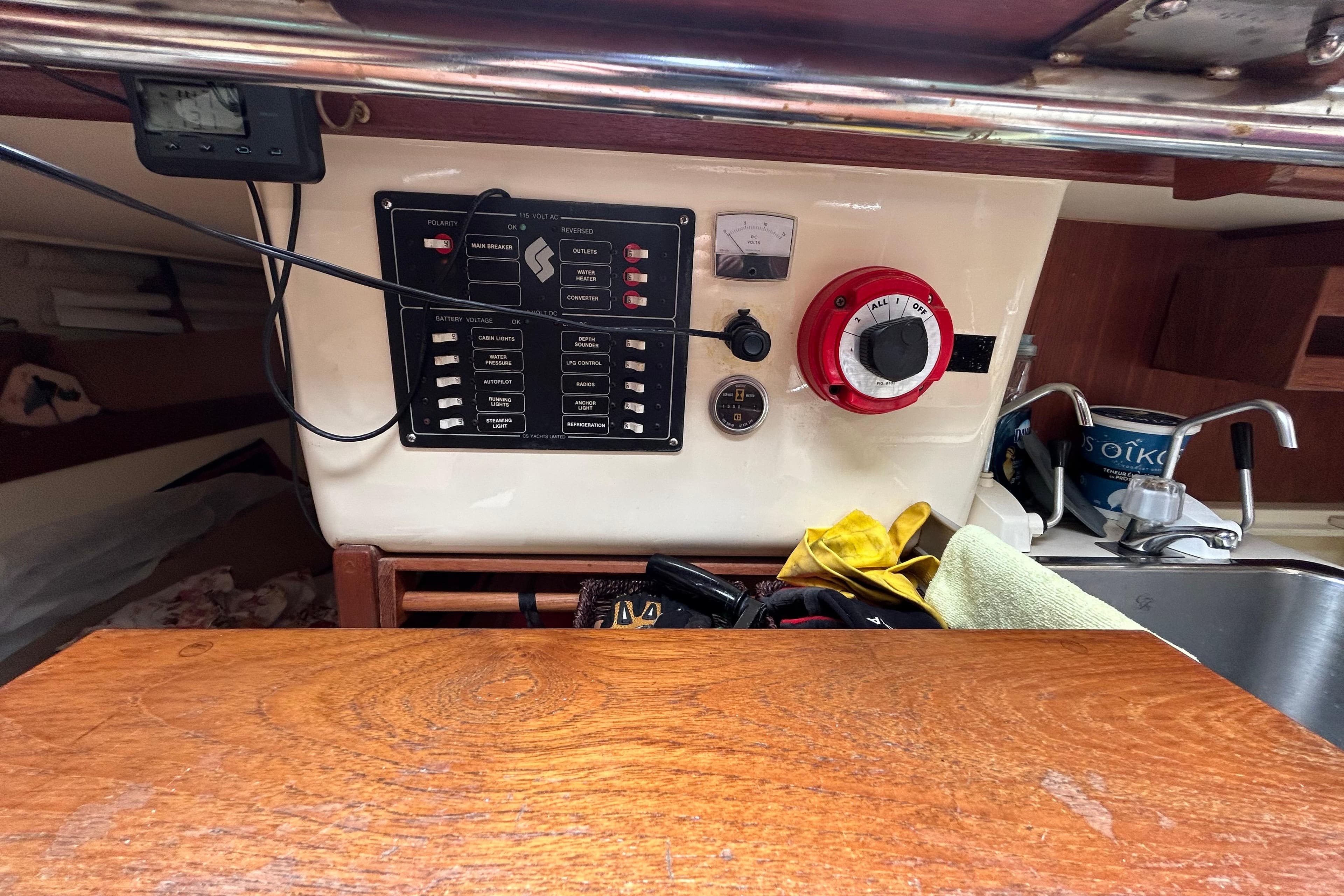 1985 CS 30 sailboat electrical panel with switches, gauge, and sink in cabin interior.