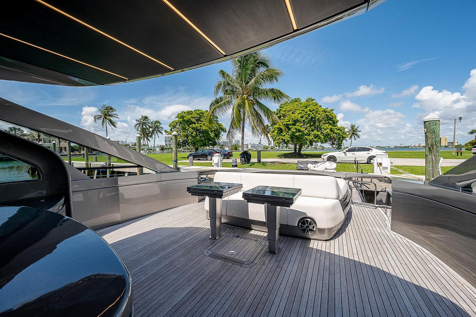 Luxurious 2015 Pershing 70 yacht deck with seating, palm trees, and blue sky backdrop.