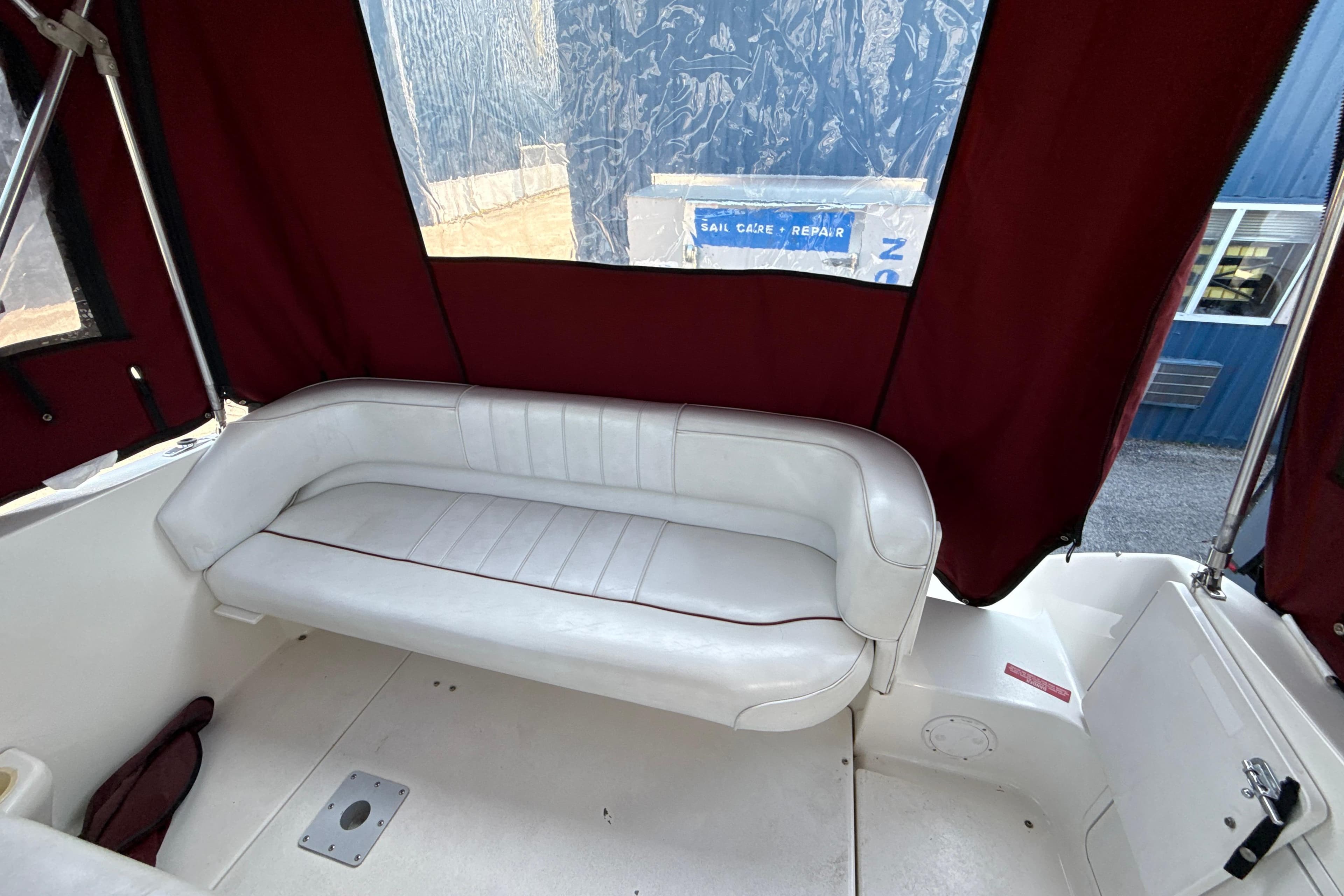 Interior of 1996 Sea Ray 240 Sundancer boat with white seating and maroon canopy.