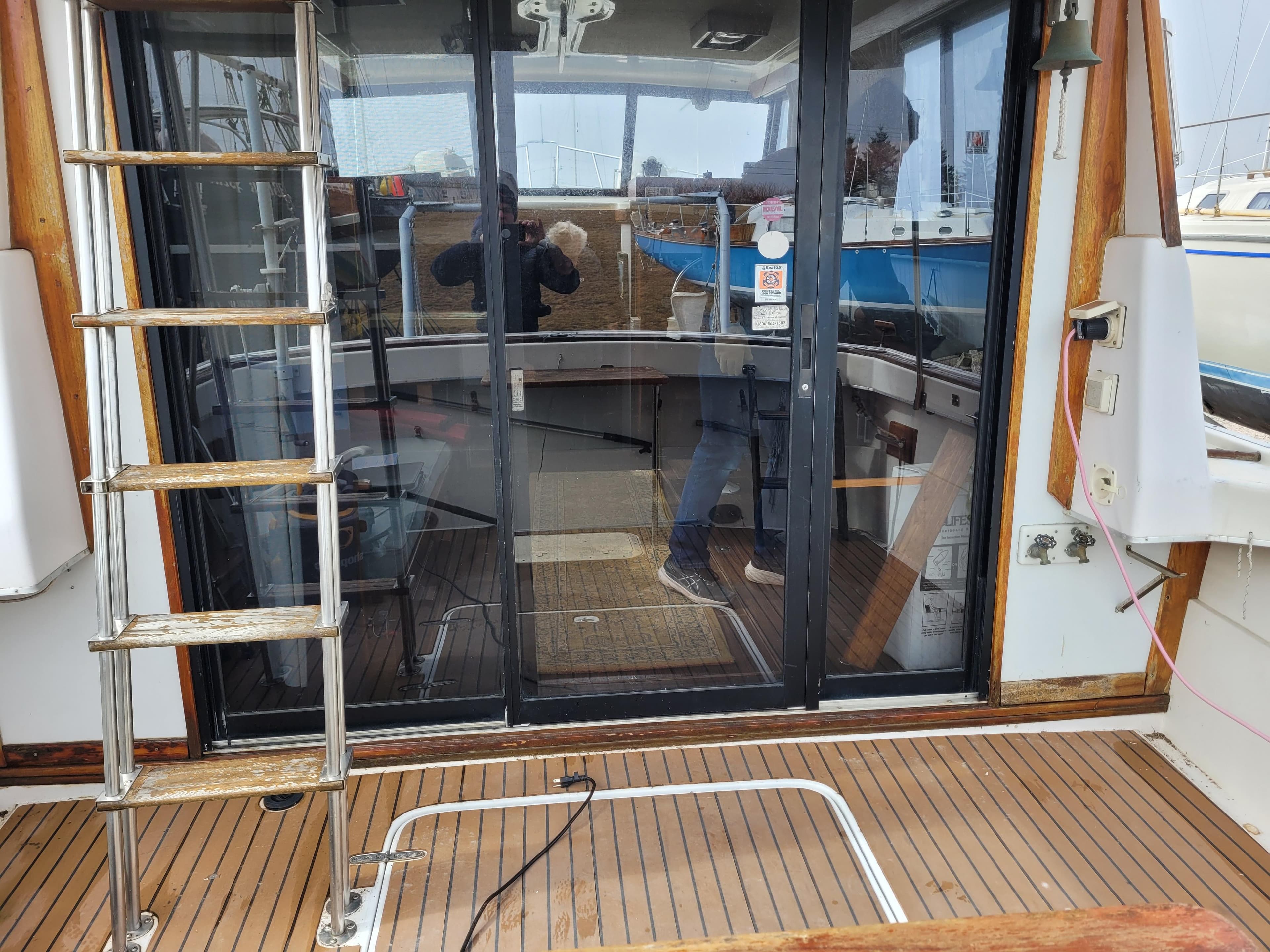 1981 Mainship 34 Trawler with wooden deck and sliding glass doors, featuring a metal ladder.