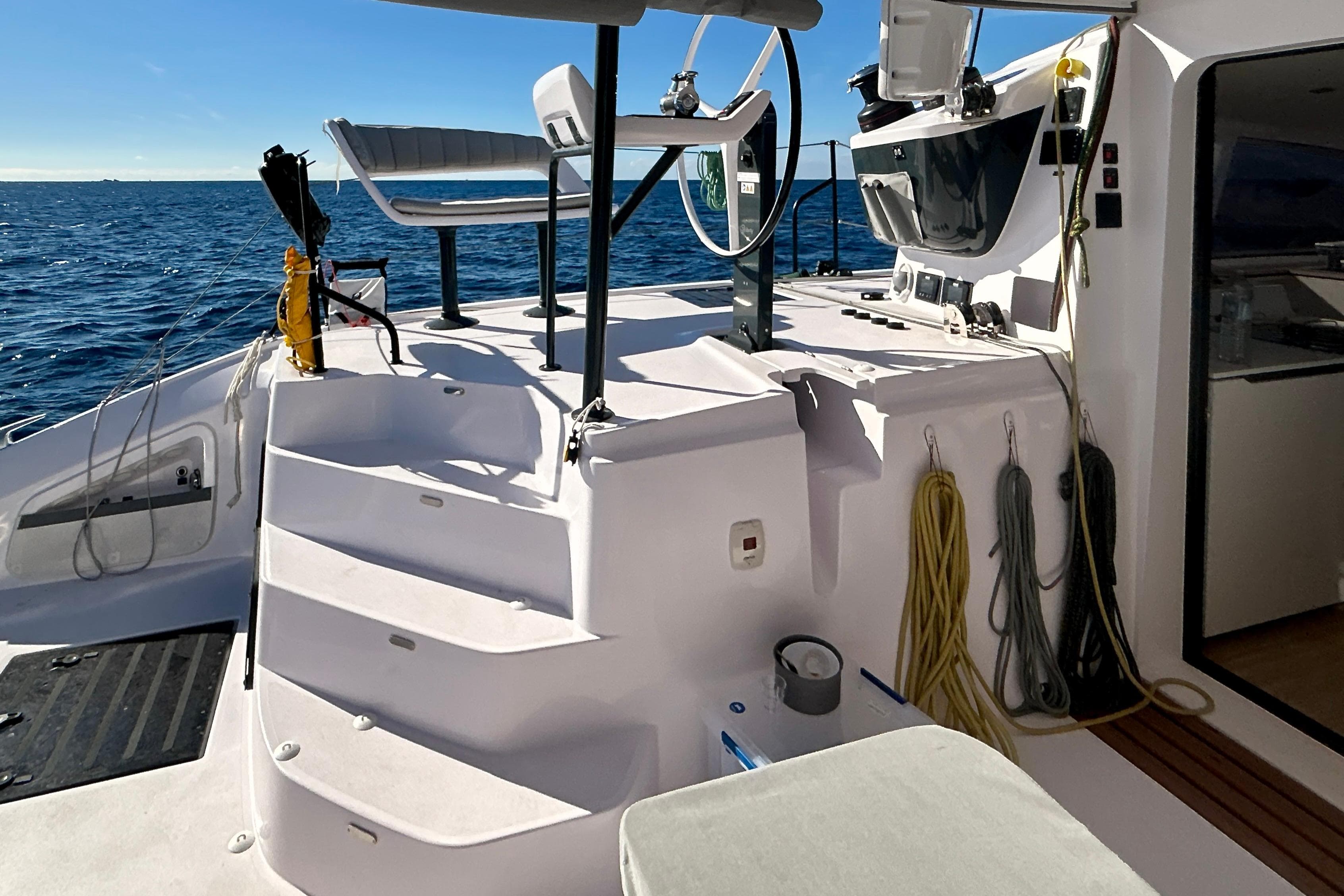 2025 Outremer 55 yacht deck with helm, ocean view, and seating area.