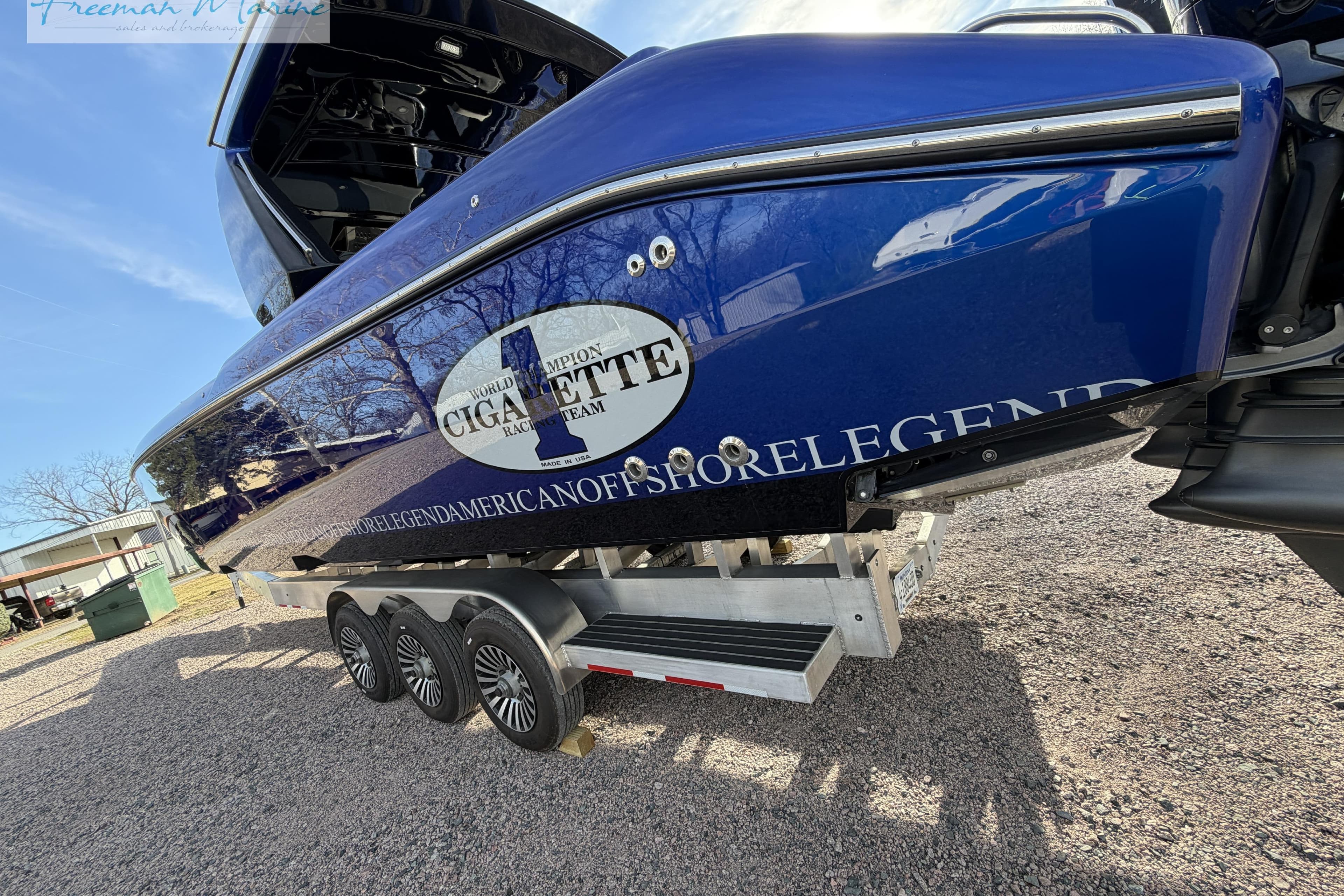 2024 Cigarette 41' Nighthawk boat on trailer, showcasing sleek blue design and triple-axle wheels.