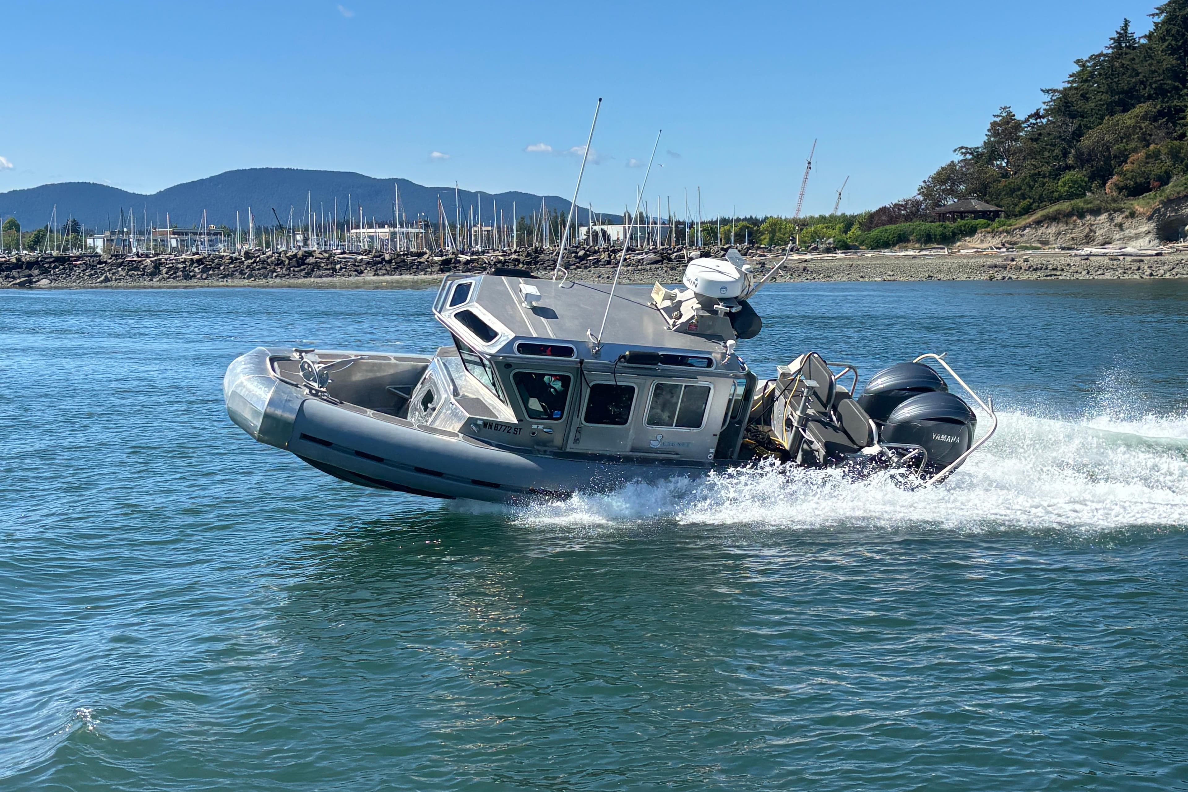 2006 SAFE Boats Defender 25 speeding on water near rocky shoreline.