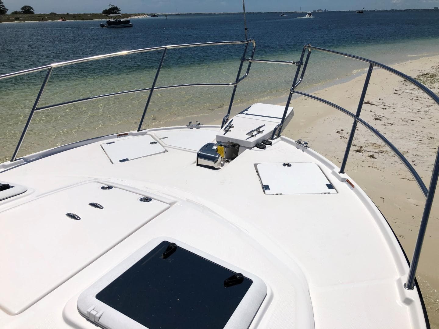 2025 Cutwater C-32 Sedan boat deck near sandy beach and calm waters.