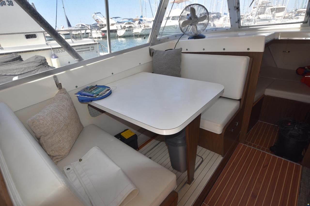 Cozy dining area inside a 2004 Outremer Standard yacht, featuring cushioned seating and a table.