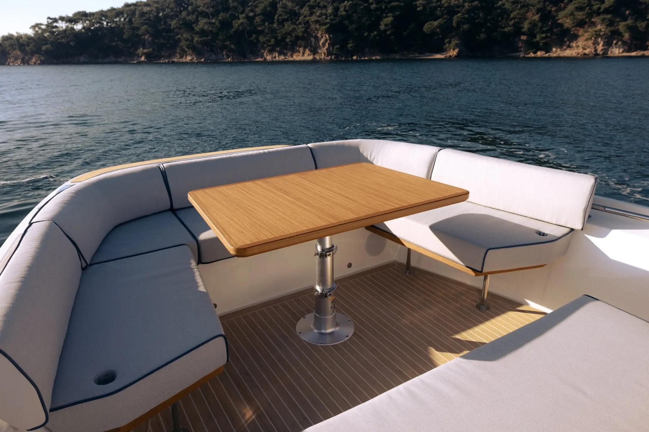 Luxurious seating area on 2026 Aiata Wayfinder 38 yacht, featuring a wooden table and scenic water view.