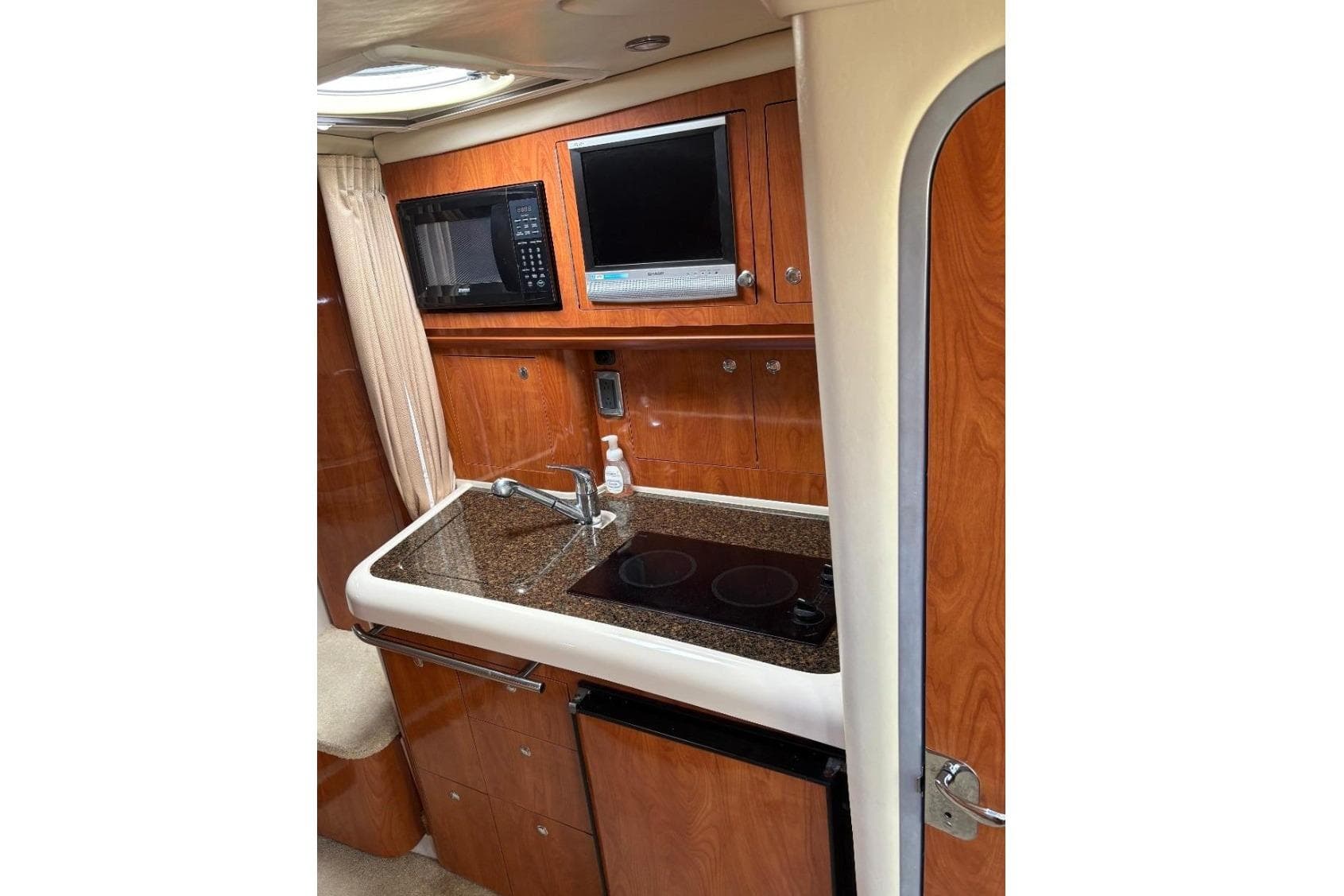 2006 Four Winns 318 Vista boat interior with kitchenette, microwave, and TV.