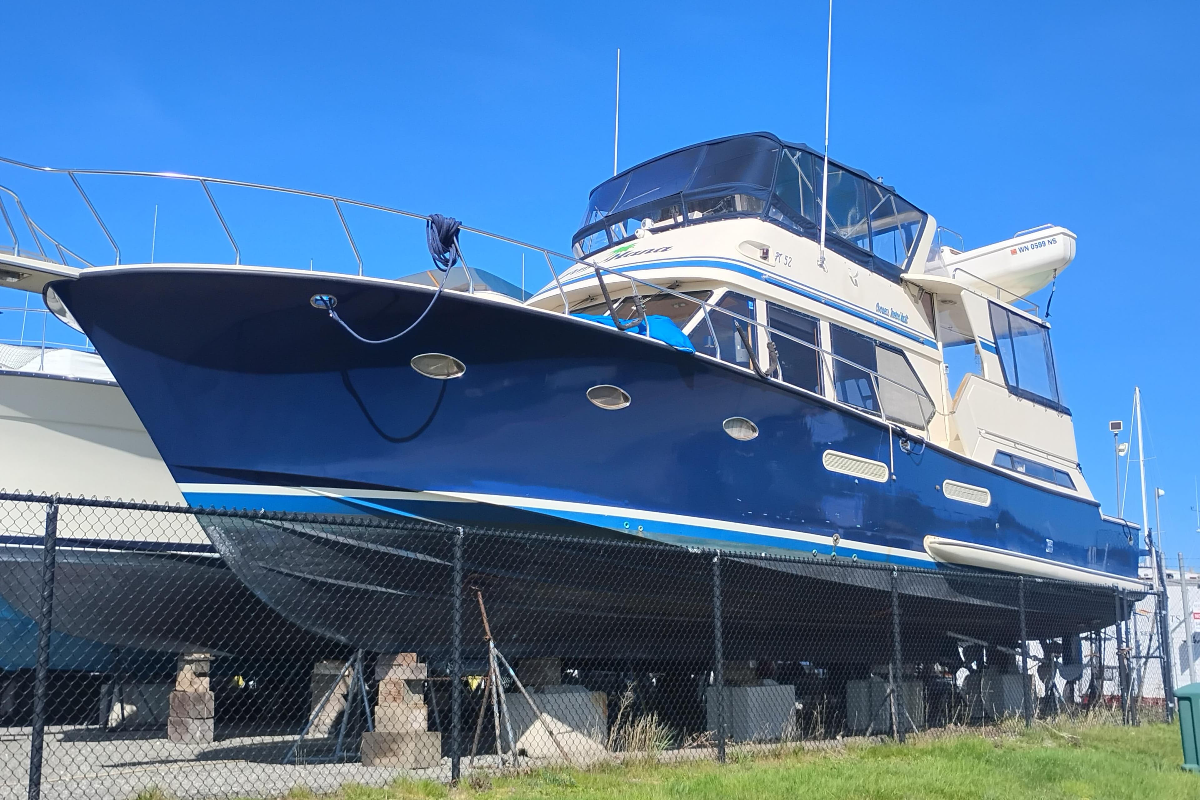 1988 PT 52 AFT Cabin Motor Yacht on dry dock, blue hull, sunny day.