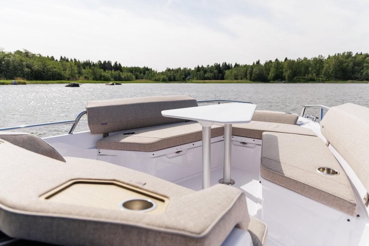 Luxurious seating on 2026 Axopar 29XC Aft Sofa, overlooking serene lake and lush greenery.