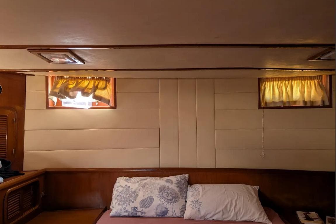 Cozy cabin interior of 1989 Angel 56 Cruiser with pillows and small windows.