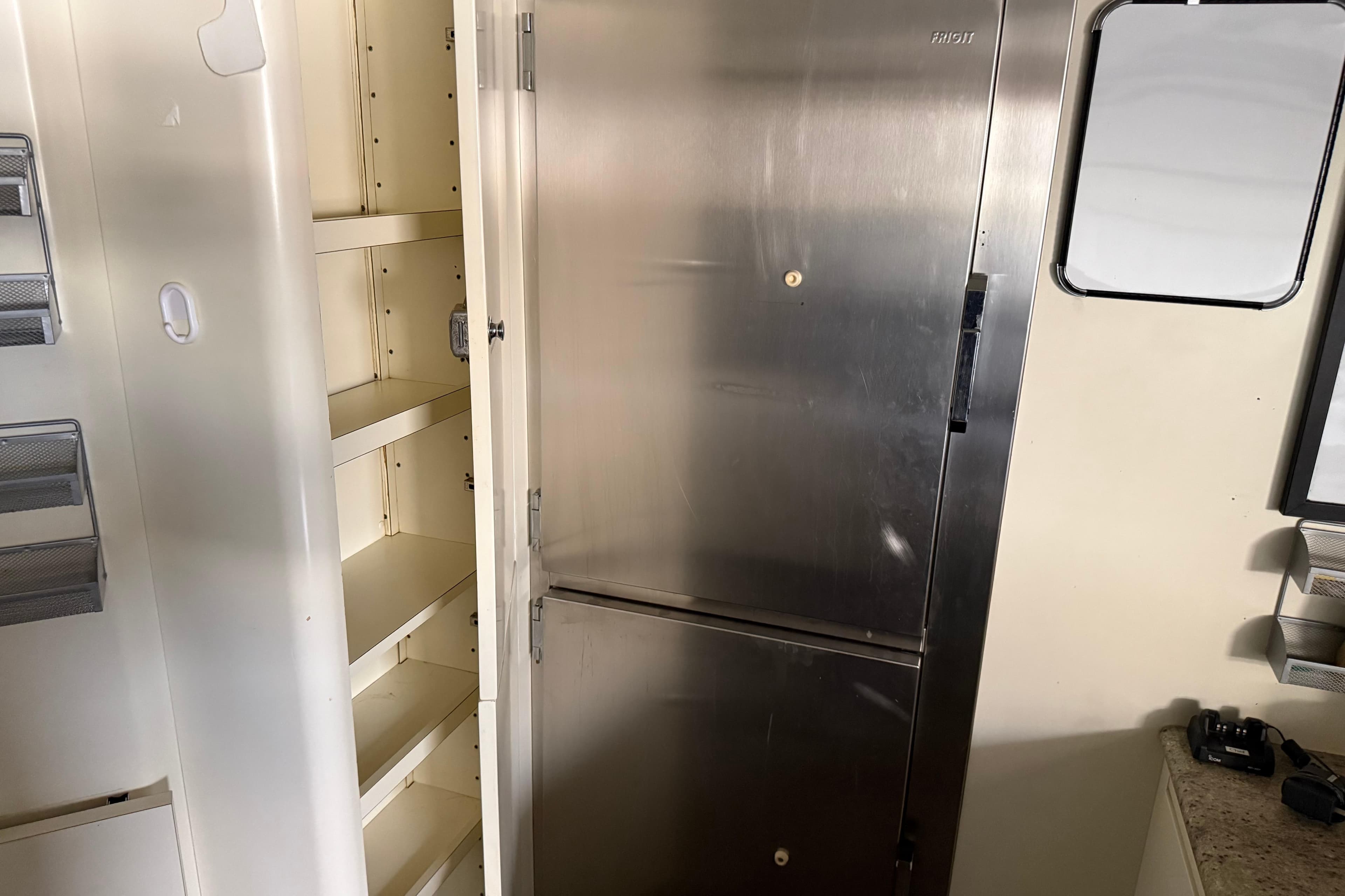 Stainless steel fridge and open shelving in a 2003 Benetti Classic 115 yacht kitchen.