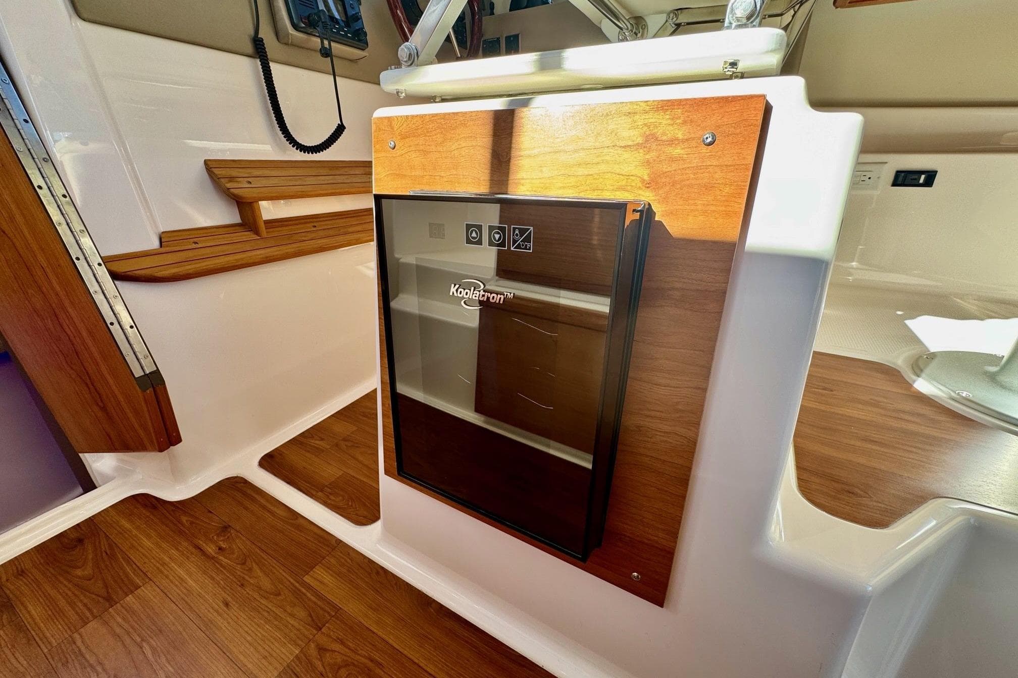 Interior of 2026 Cutwater C-32 CB boat with wooden flooring and compact fridge.