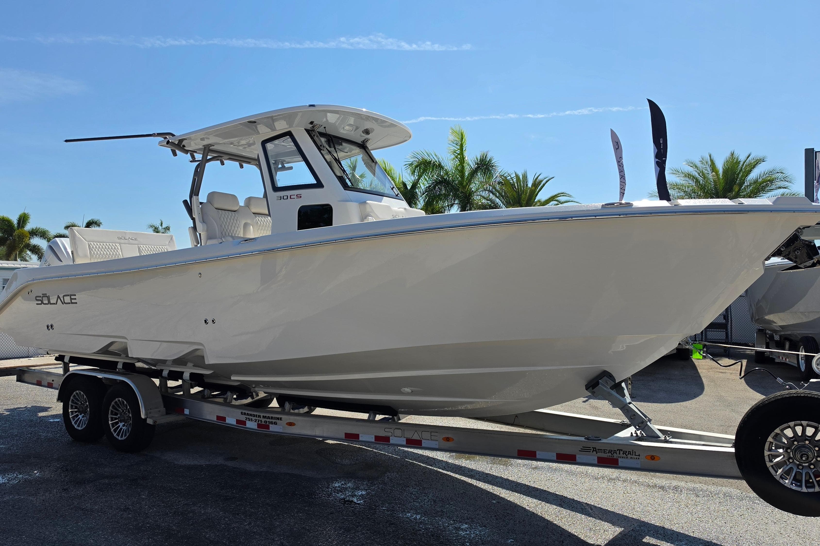 2026 Solace 30CS boat on trailer, displayed outdoors with palm trees in background.