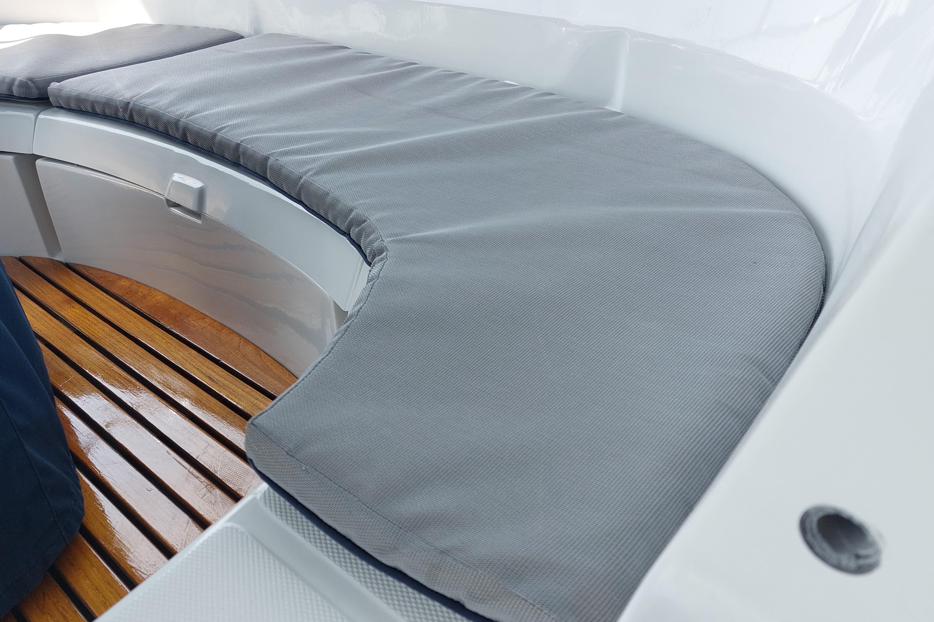 Cushioned seating area on a 2002 Hunter 380 sailboat with wooden flooring.
