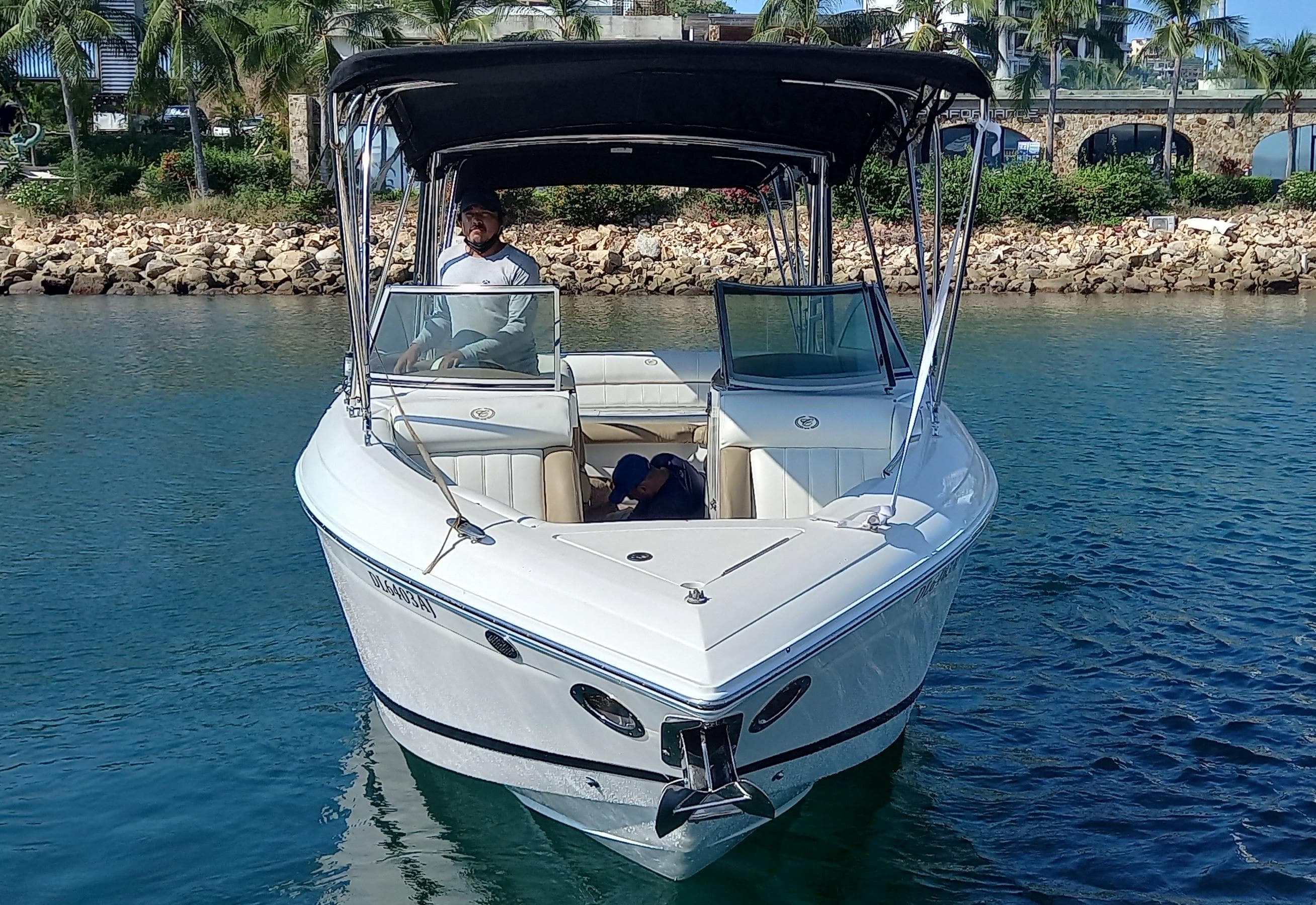 2011 Cobalt 276 boat on water, with canopy and driver, near rocky shoreline.