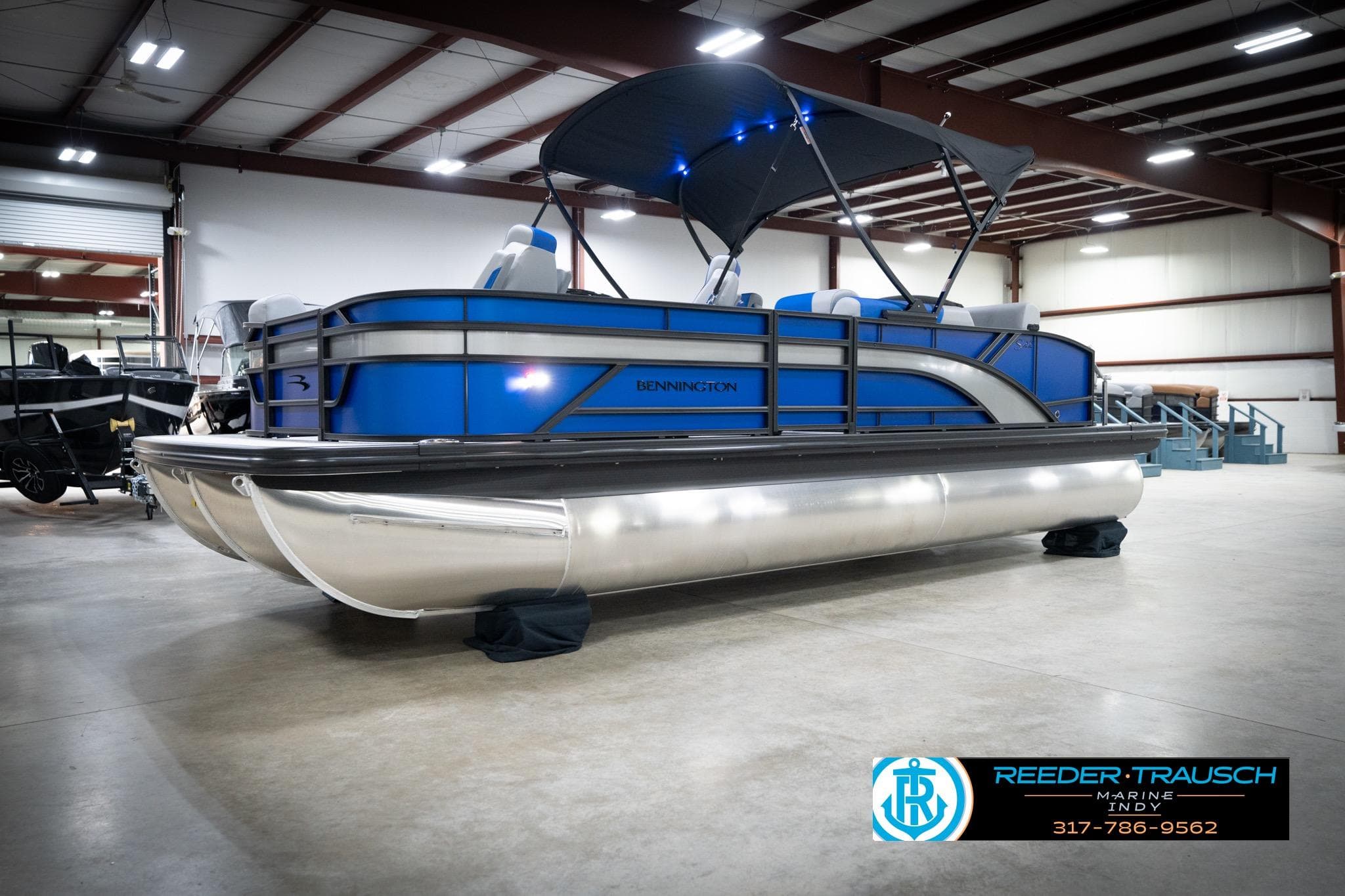 2026 Bennington 22 SSB pontoon boat in showroom with blue accents and canopy.