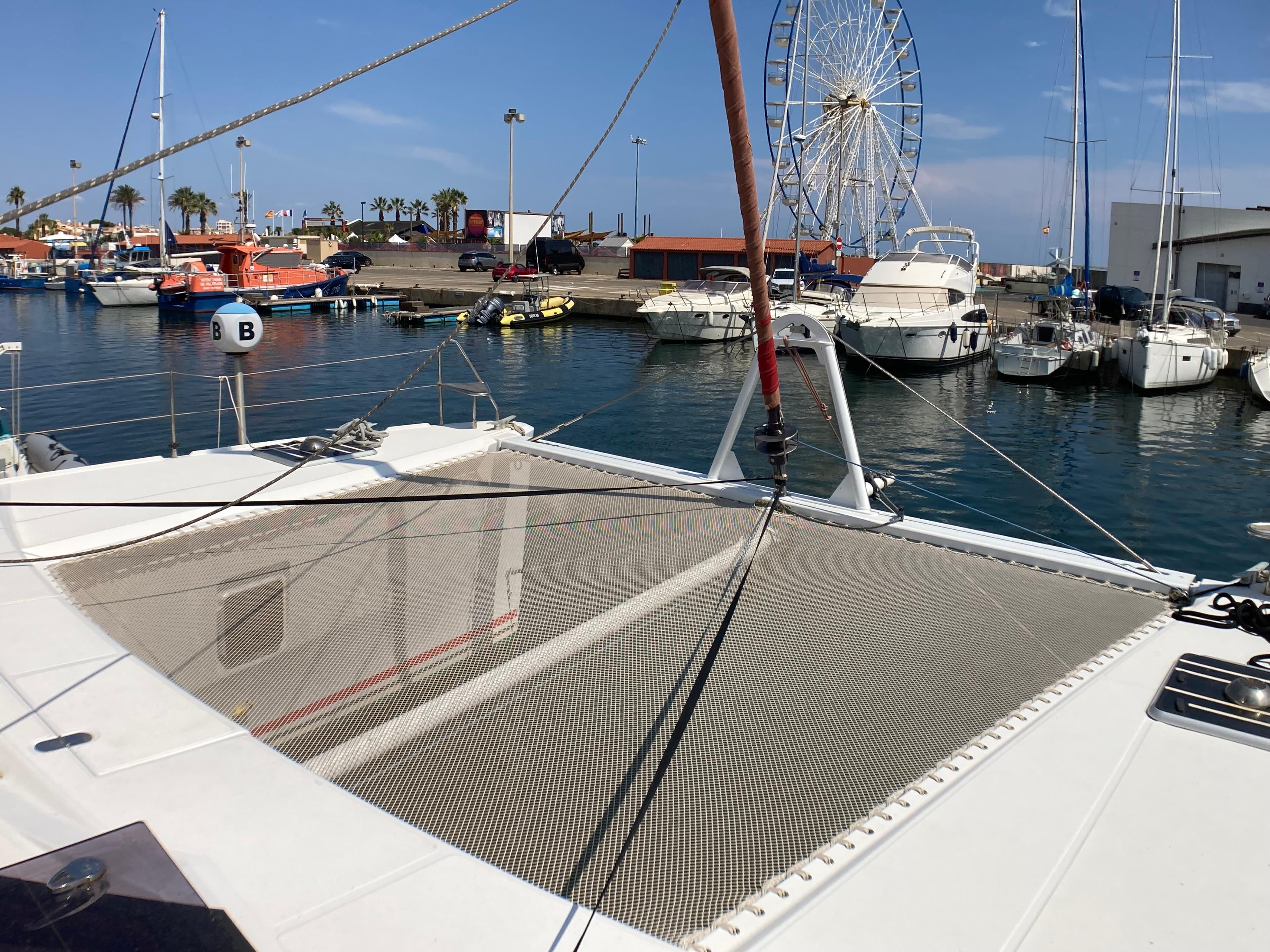Catamaran Phisa XV 2010 docked at marina with ferris wheel in background.