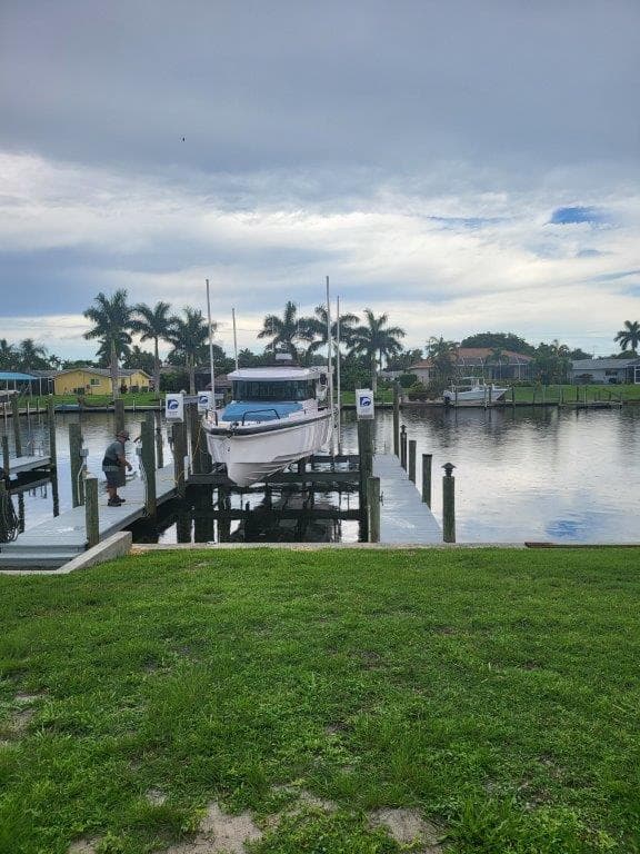 2024 Axopar 37 XC CROSS CABIN docked by a serene waterfront with palm trees.
